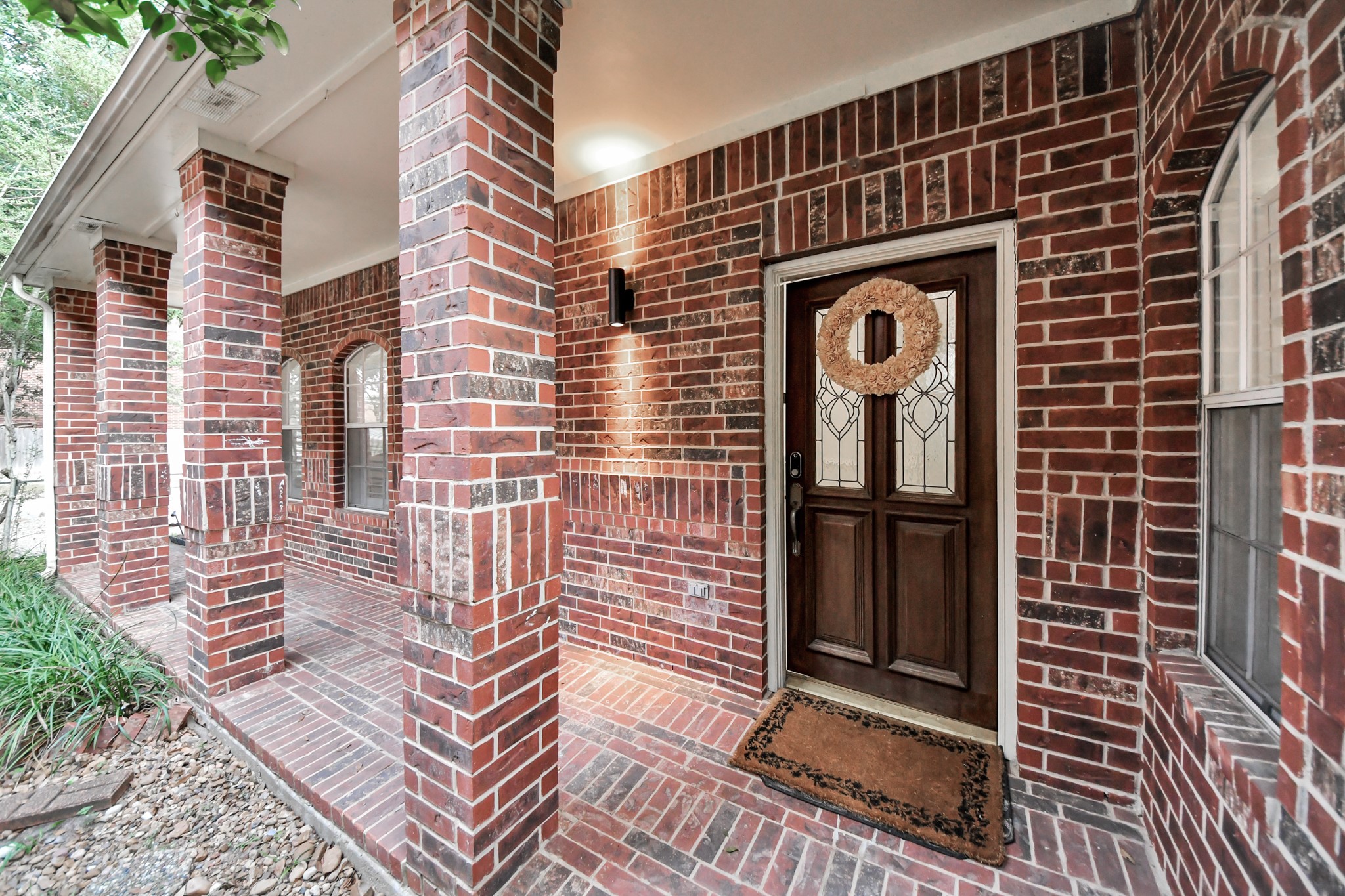 A covered front porch with brick columns and a beautiful front door welcomes you home.