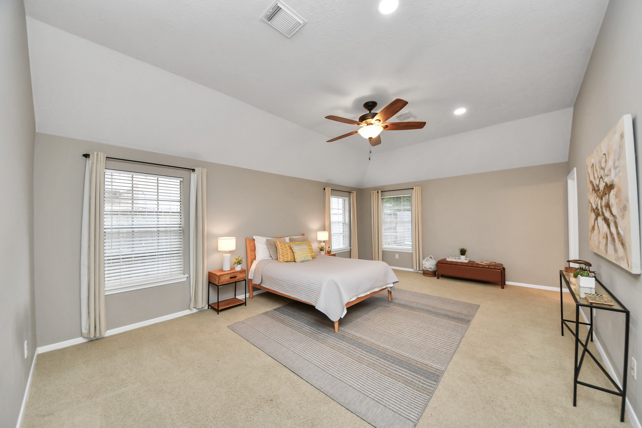 The spacious primary bedroom features high ceilings, large windows, and plenty of room for your furniture, with space left for a sitting area.