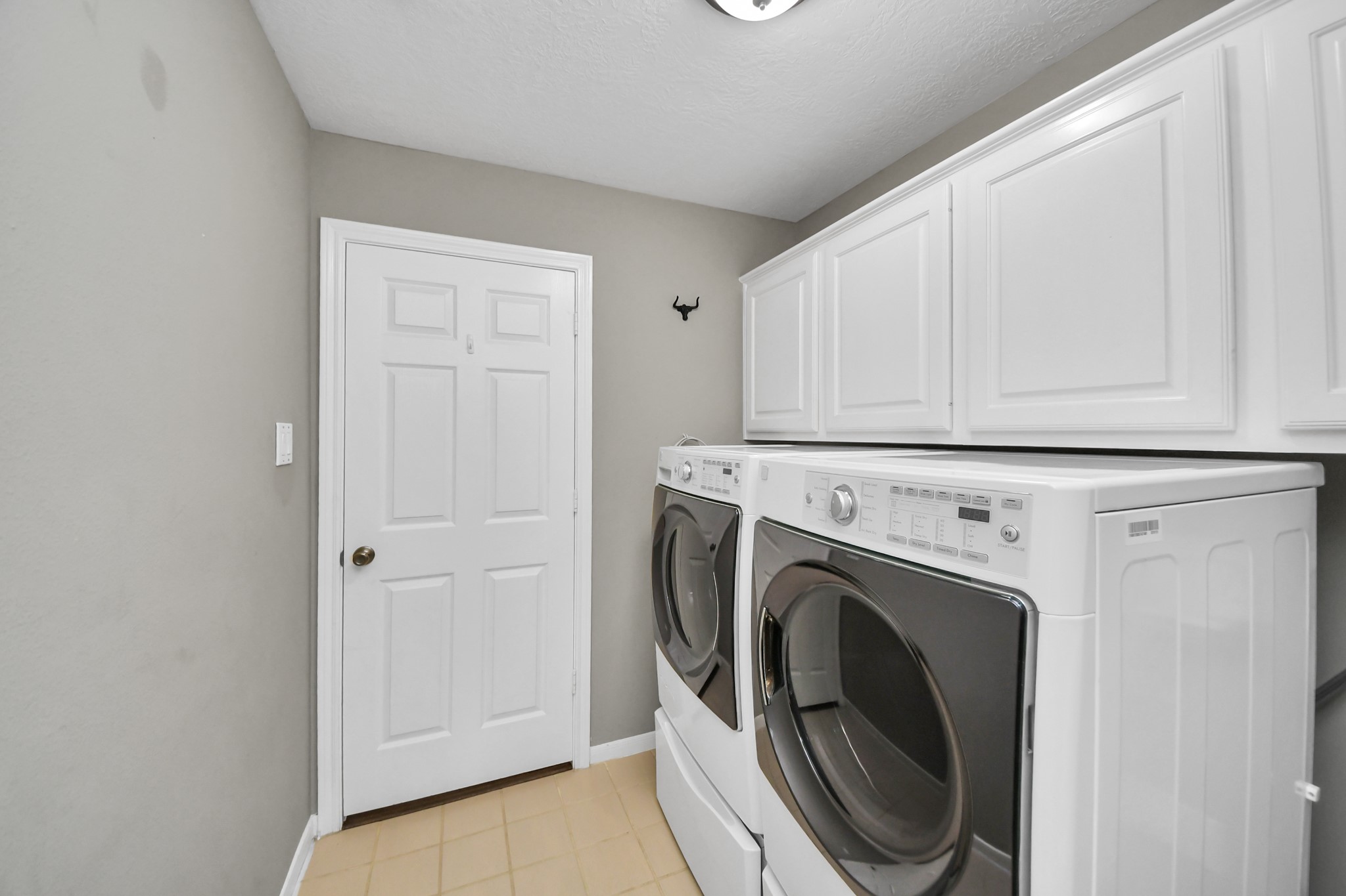The laundry room has space for a side-by-side washer and dryer, with overhead cabinets to keep laundry supplies tucked away.