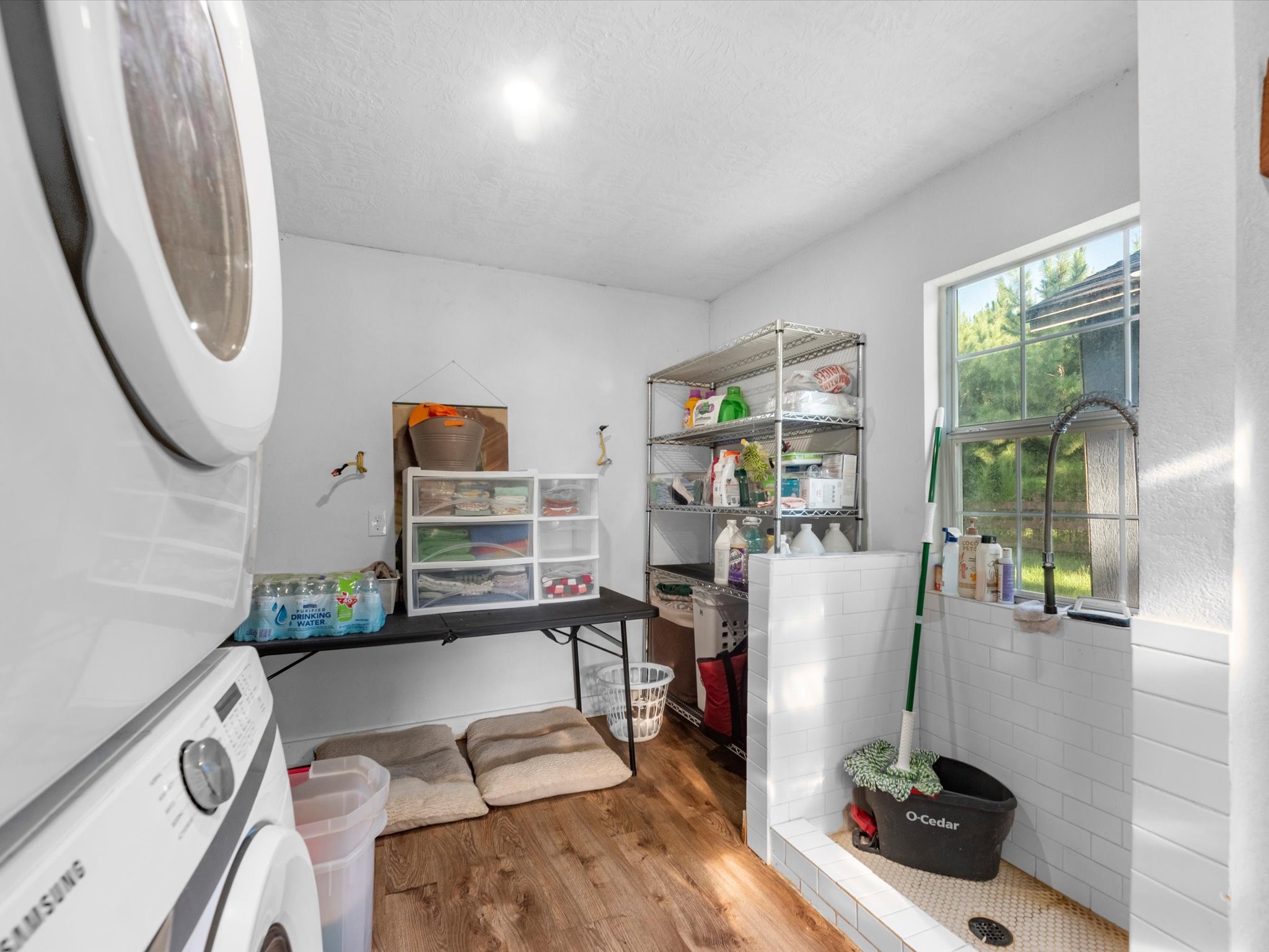 Convenient utility room featuring a bonus shower area, perfect for washing pets, muddy shoes, or other everyday cleanup needs.