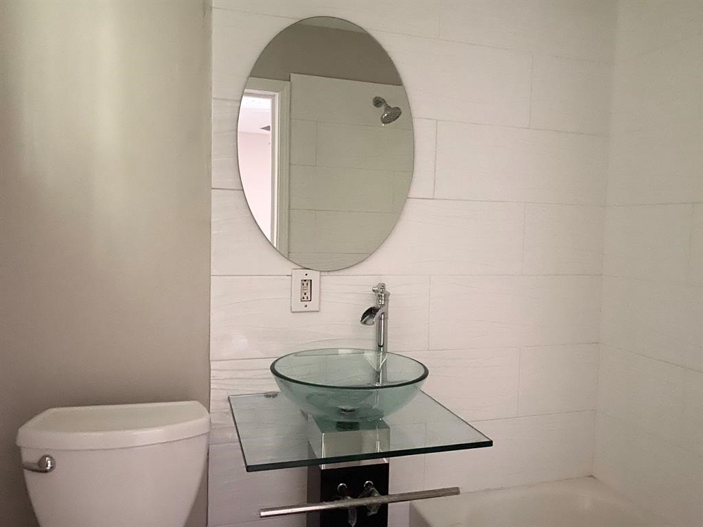 Modern bathroom with sleek glass sink and oval mirror, complemented by a minimalist design.