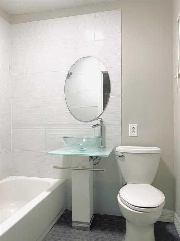 Modern bathroom featuring a sleek glass vessel sink, oval mirror, and elegant gray tiling, creating a clean and contemporary space.