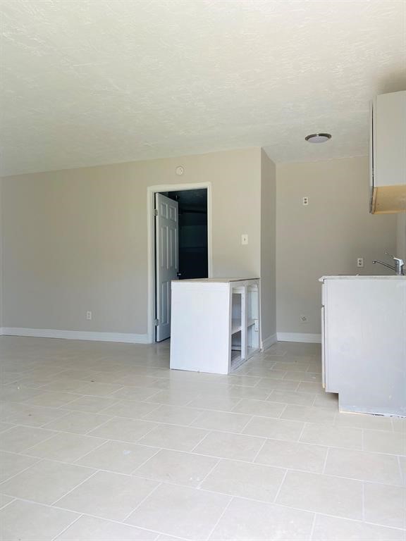 Bright and open interior with neutral tones, tile flooring, and a partially finished kitchen, offering a blank canvas for customization.