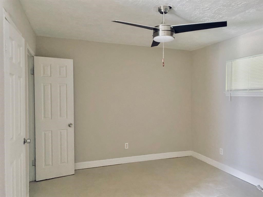 Bright and inviting room featuring neutral walls, tiled flooring, a modern ceiling fan, and ample natural light from a cozy window.