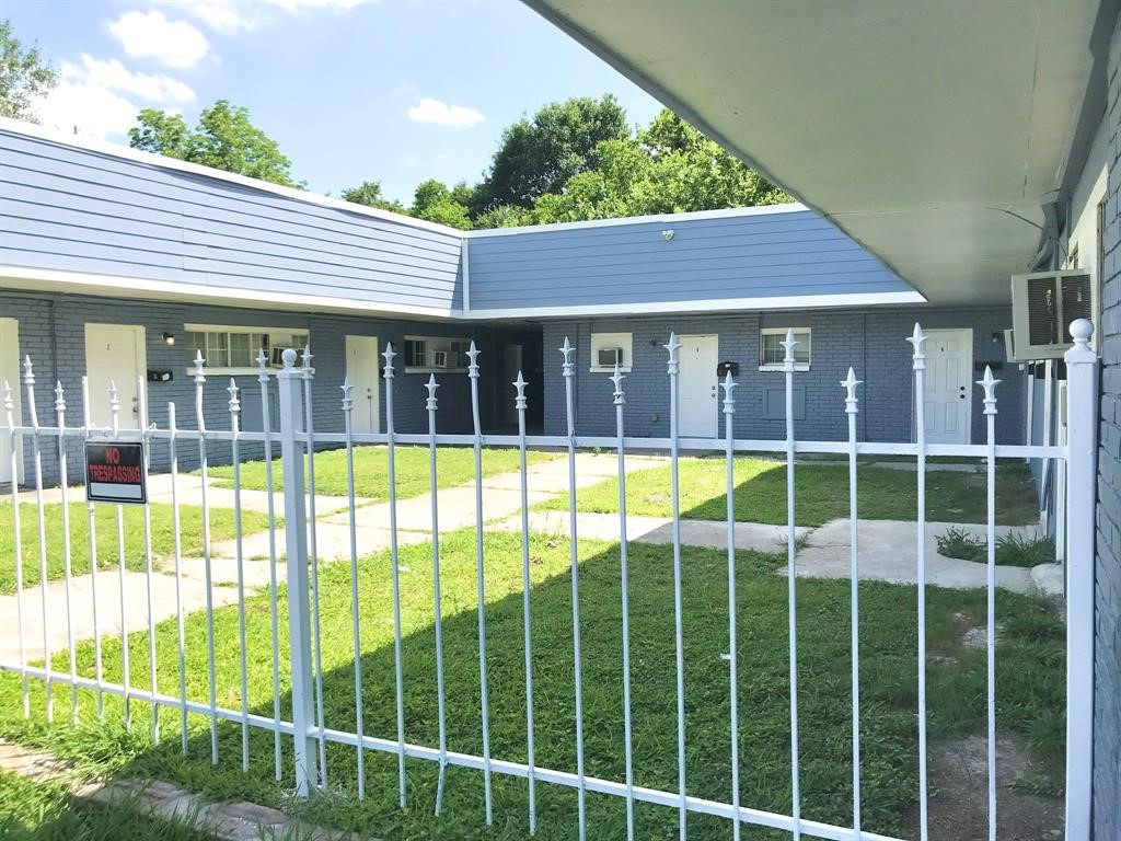 Charming single-story property with a modern blue exterior, nestled behind a decorative white fence, offering privacy and a welcoming atmosphere.