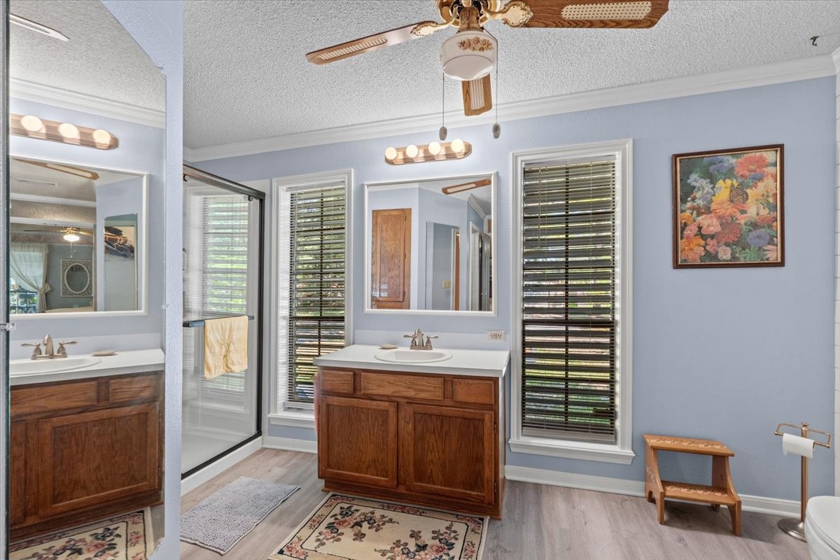 Primary bathroom with vinyl flooring, updated shower and double walk-in closets.