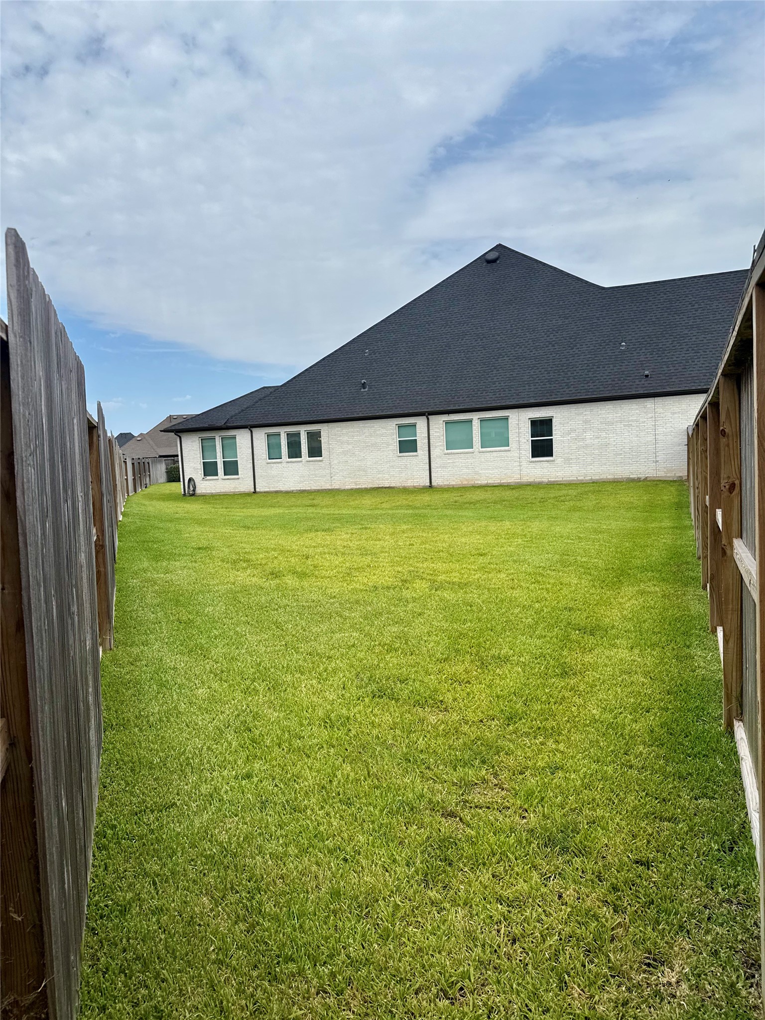 Expansive backyard with lush green lawn, perfect for outdoor activities and relaxation, ample space for a pool and enclosed by a wooden privacy fence.