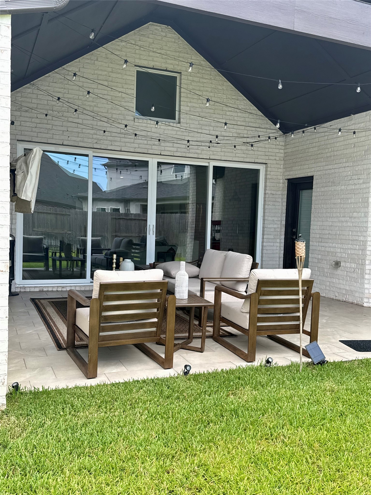 Charming outdoor patio with cozy seating, string lights, and a spacious sliding door, perfect for relaxing and entertaining.
