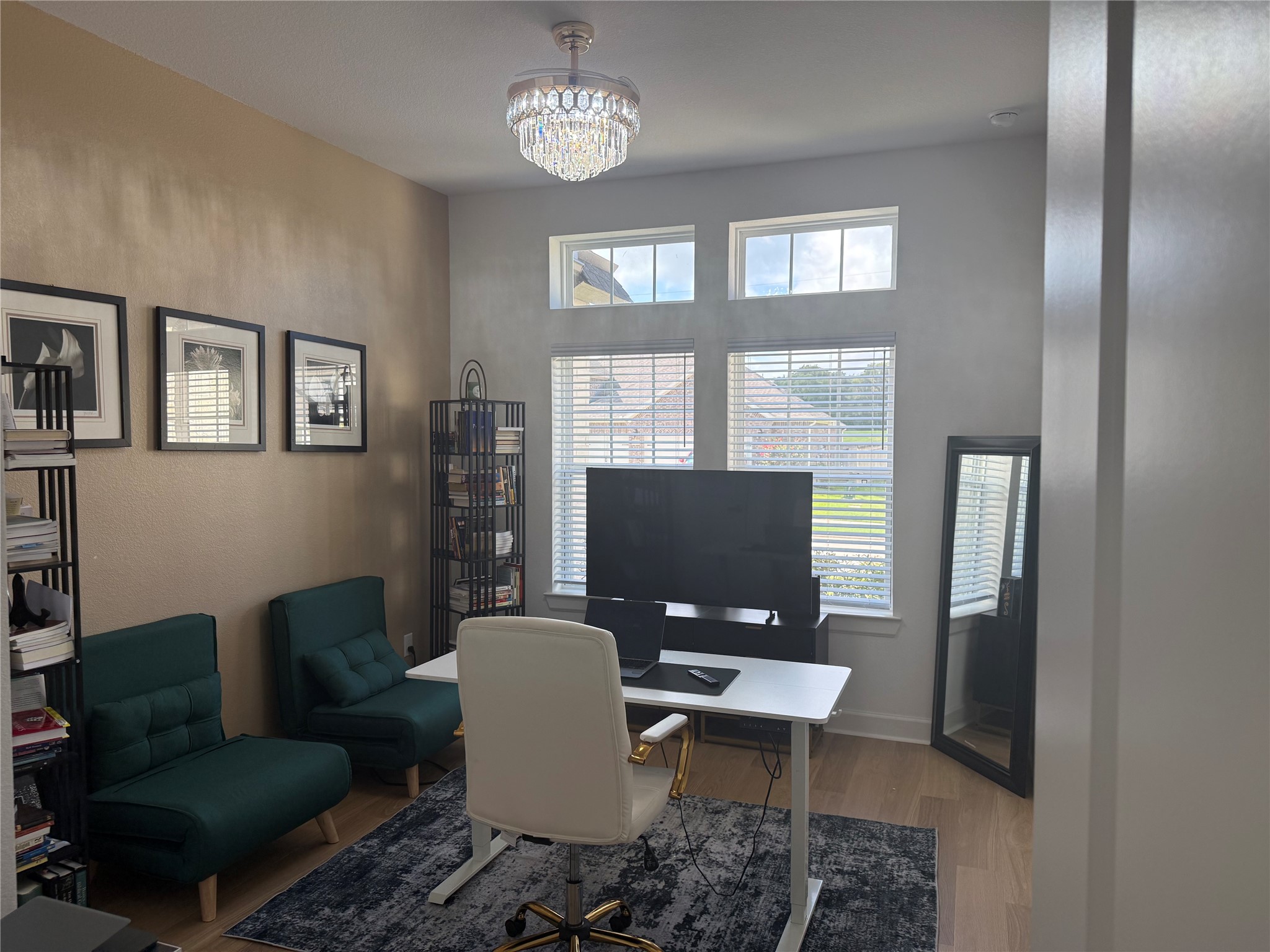 Utilize this 4th bedroom as an inviting office space with large windows, elegant chandelier, and stylish decor, perfect for productivity and comfort.