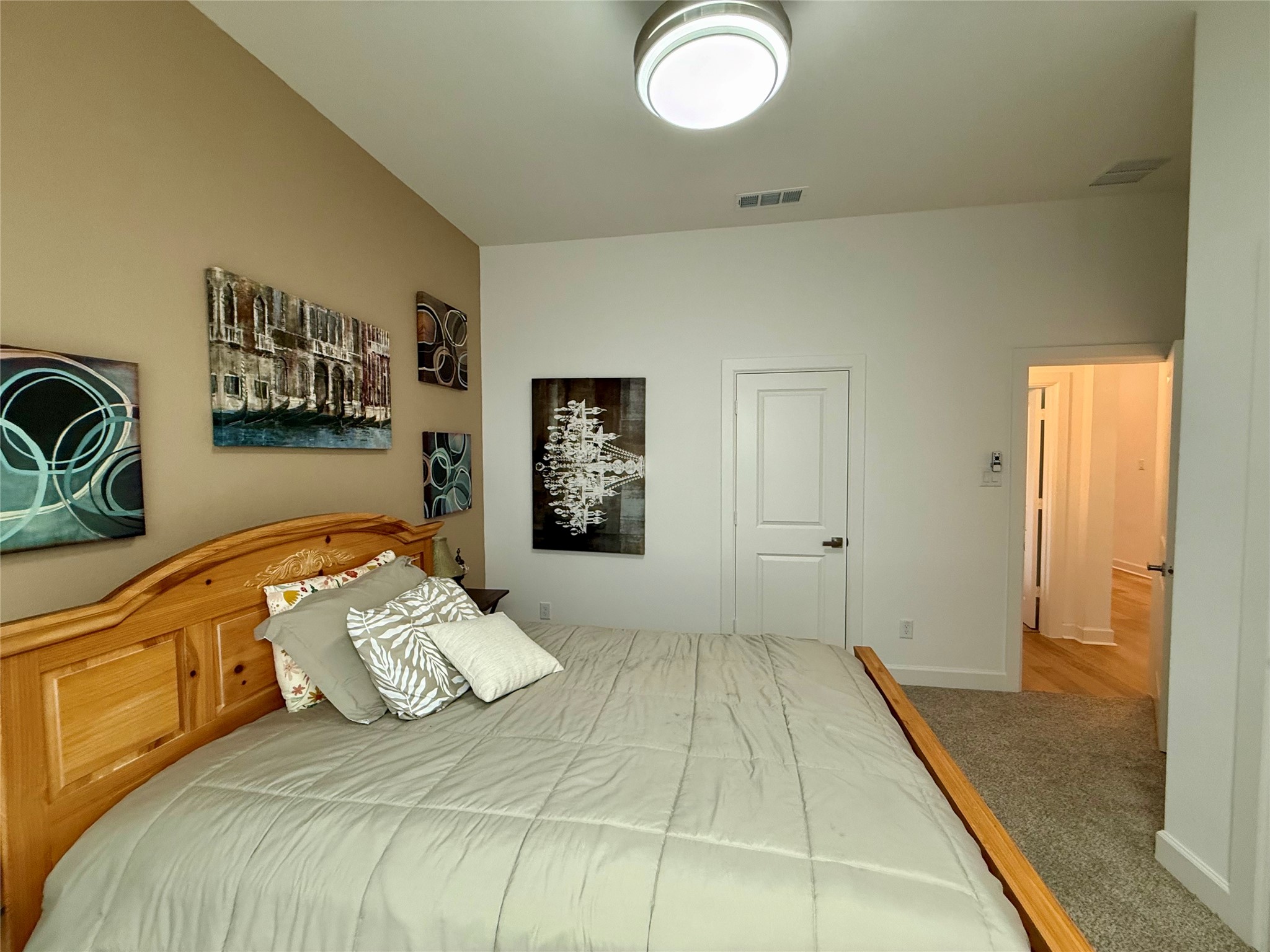 Cozy bedroom(3) with a wooden bed frame, modern lighting, and tasteful wall art, offering a serene retreat.