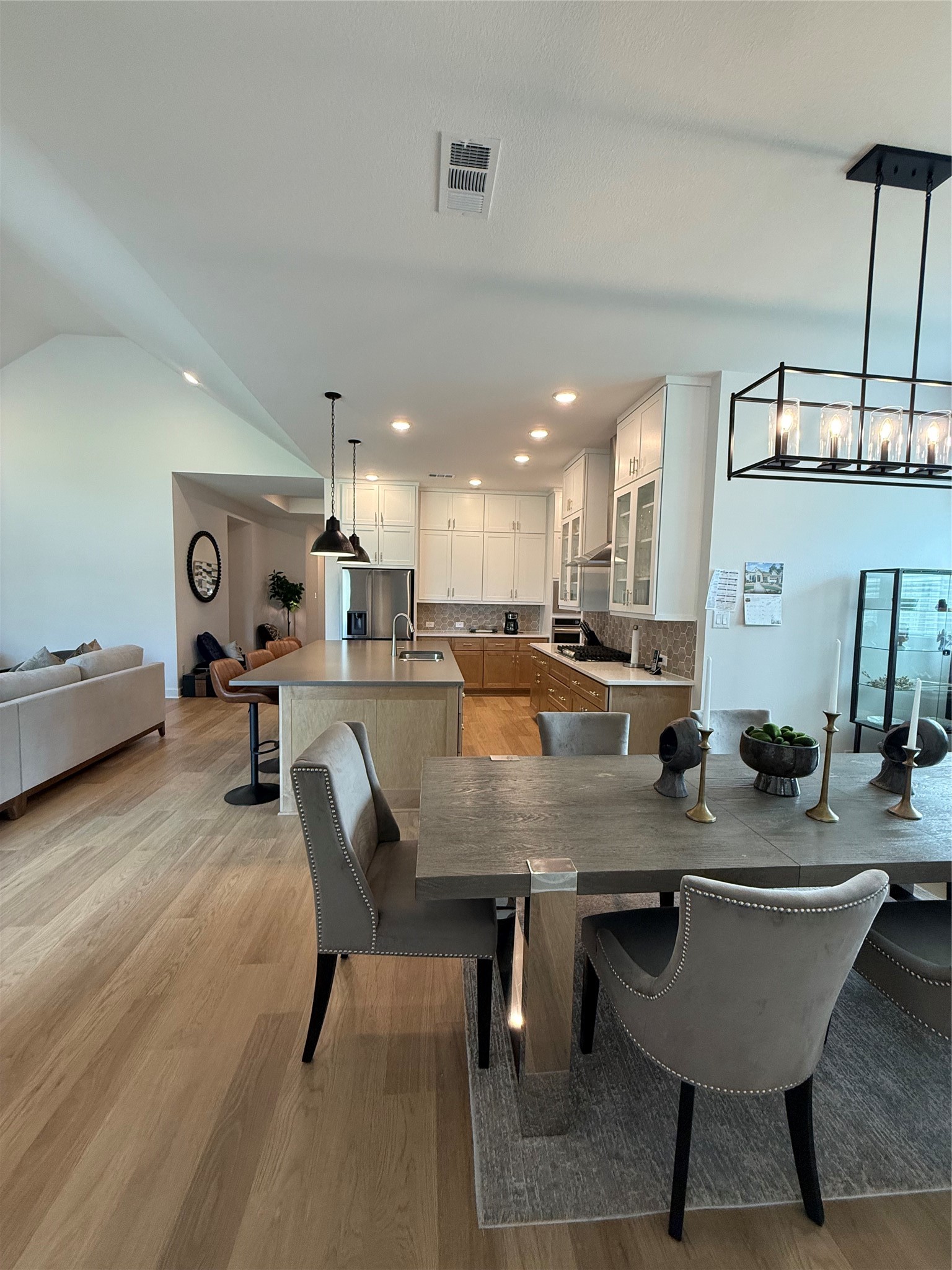 Experience modern elegance in this open-concept living space featuring a stylish kitchen with white cabinetry, a spacious island, and contemporary lighting. Perfect for entertaining, the adjoining dining area seamlessly flows into a cozy living room.