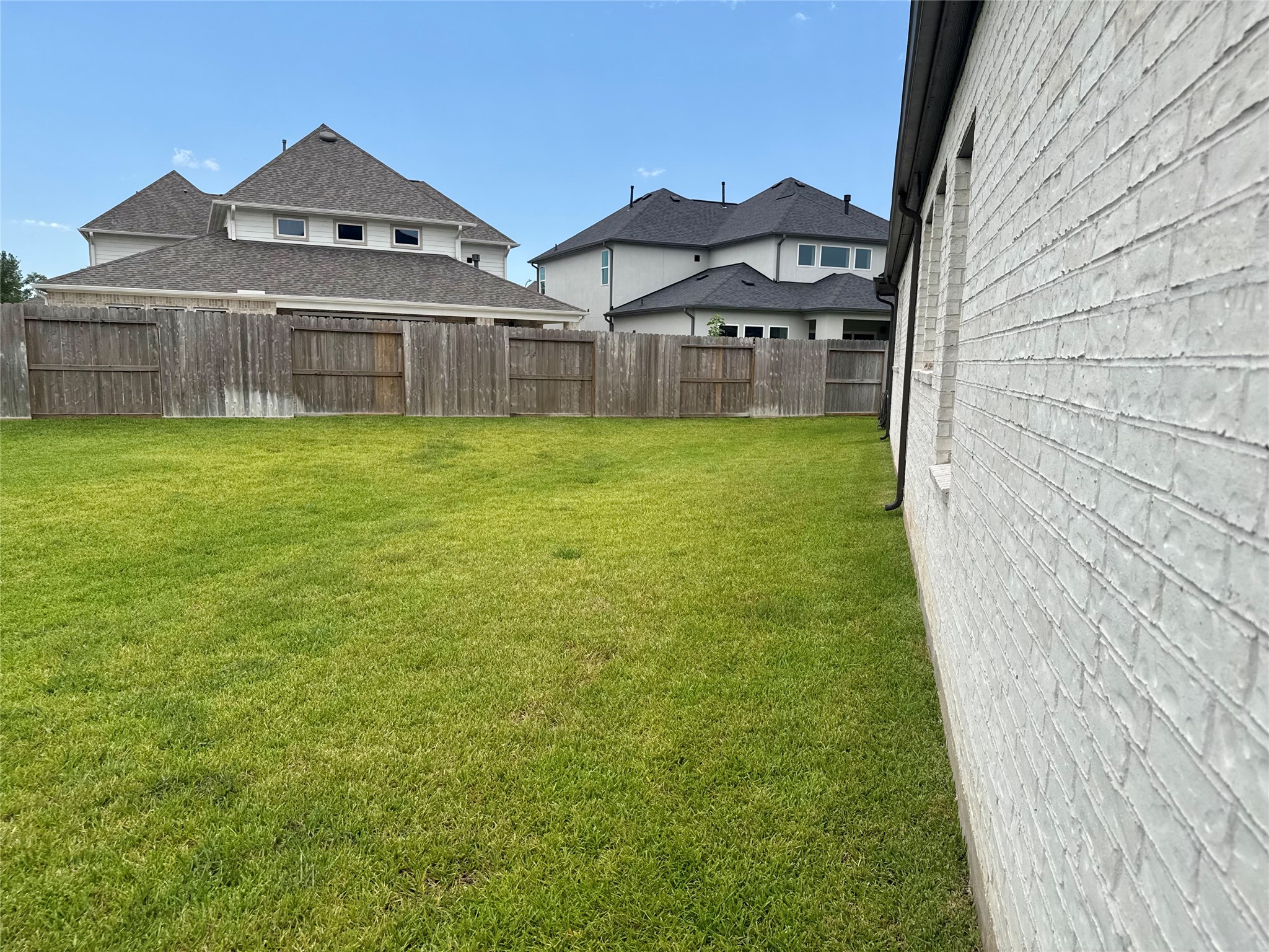 Expansive backyard with lush green lawn, bordered by a sturdy wooden fence for privacy, perfect for outdoor activities and relaxation.