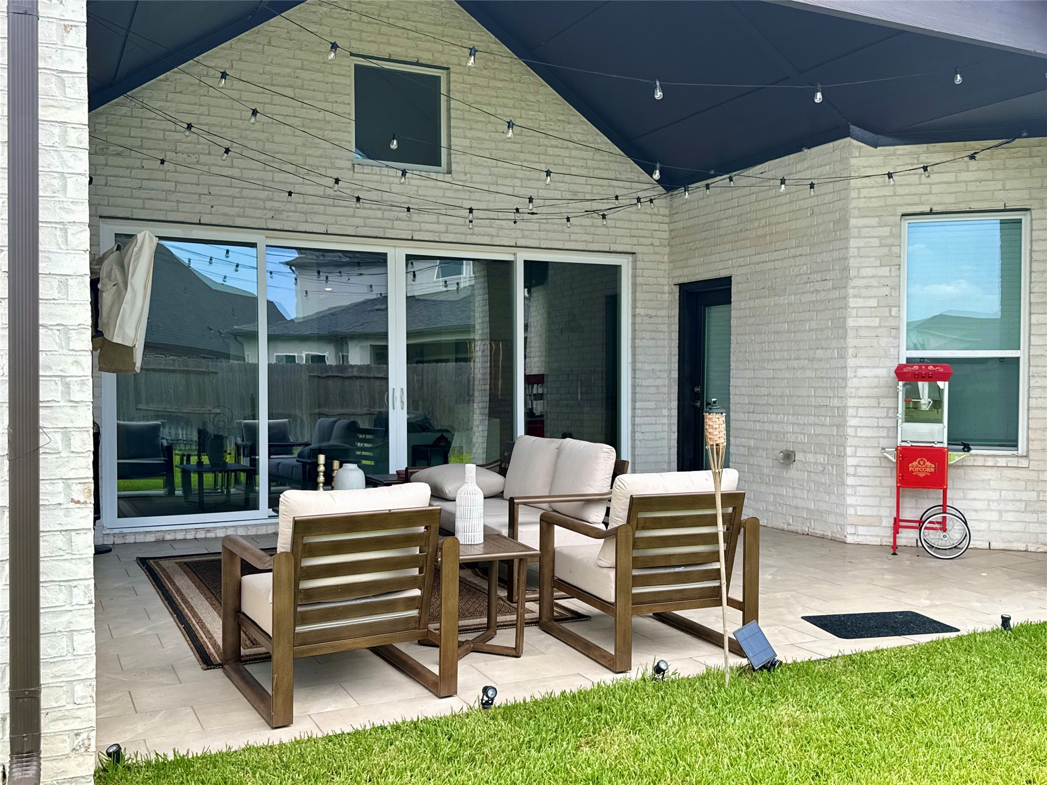Charming covered patio with comfortable seating, furnished showing off string lights, perfect for outdoor entertaining.