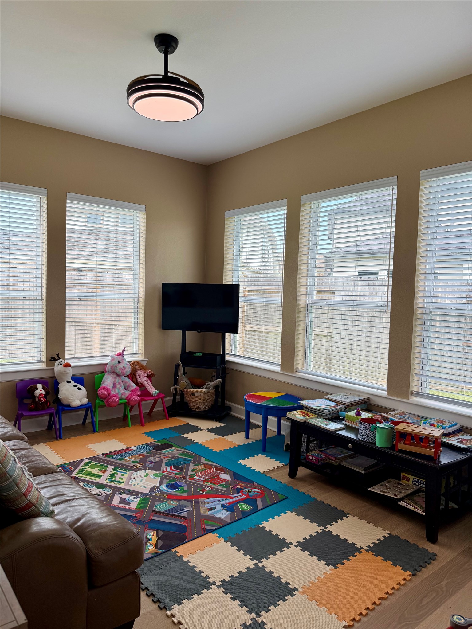 Retreat area utilized as  a Bright and inviting playroom featuring large windows, colorful foam flooring, and ample space for toys and activities.