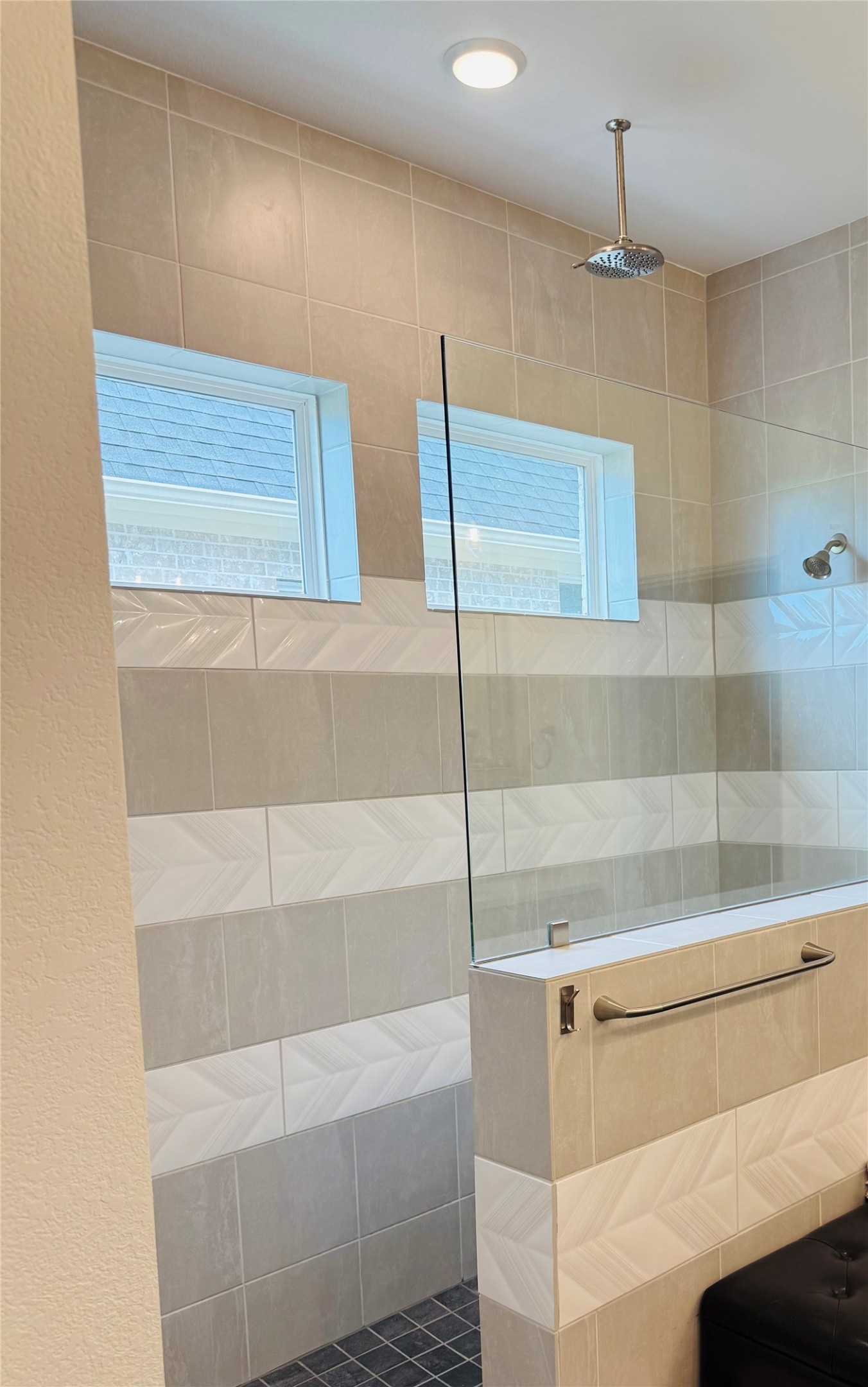 Elegant walk-in shower featuring modern tiling, dual windows for natural light, and a sleek overhead rain showerhead for a spa-like experience.