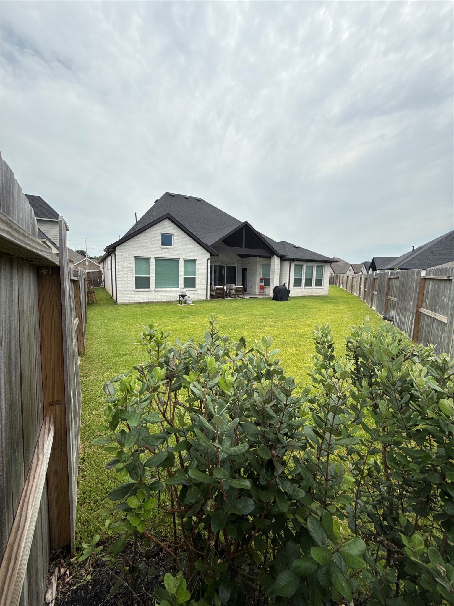 Expansive backyard with lush green lawn, perfect for outdoor activities, featuring a modern home with a spacious covered patio ideal for relaxation and entertaining.