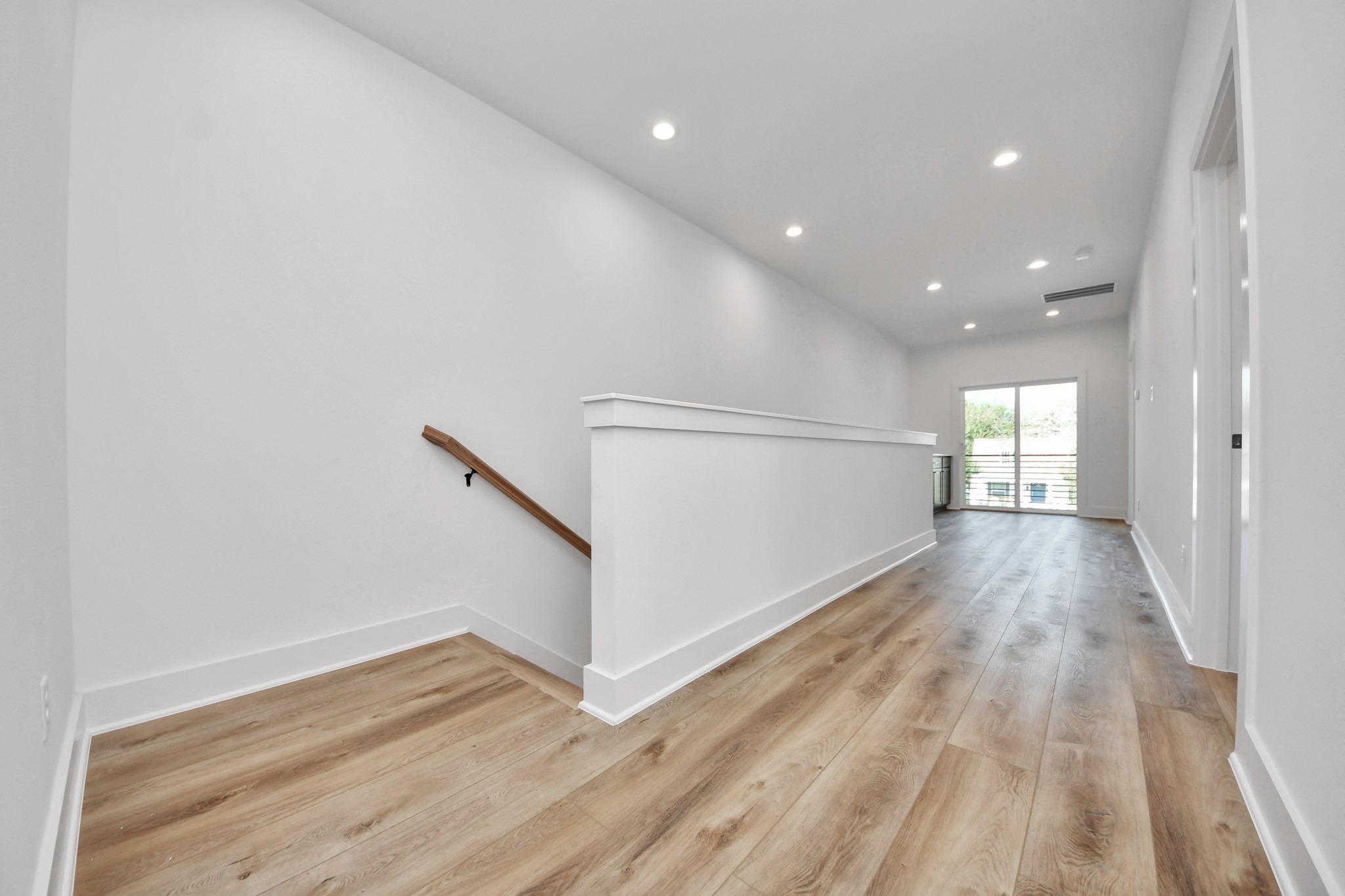 Unit B upstairs hallway featuring wood-look flooring and access to the private balcony.
