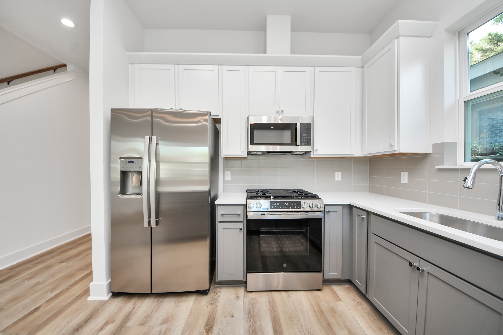 Unit A kitchen featuring white cabinetry, gray lower cabinets, and stainless steel appliances. Unit A kitchen featuring white cabinetry, gray lower cabinets, and stainless steel appliances.