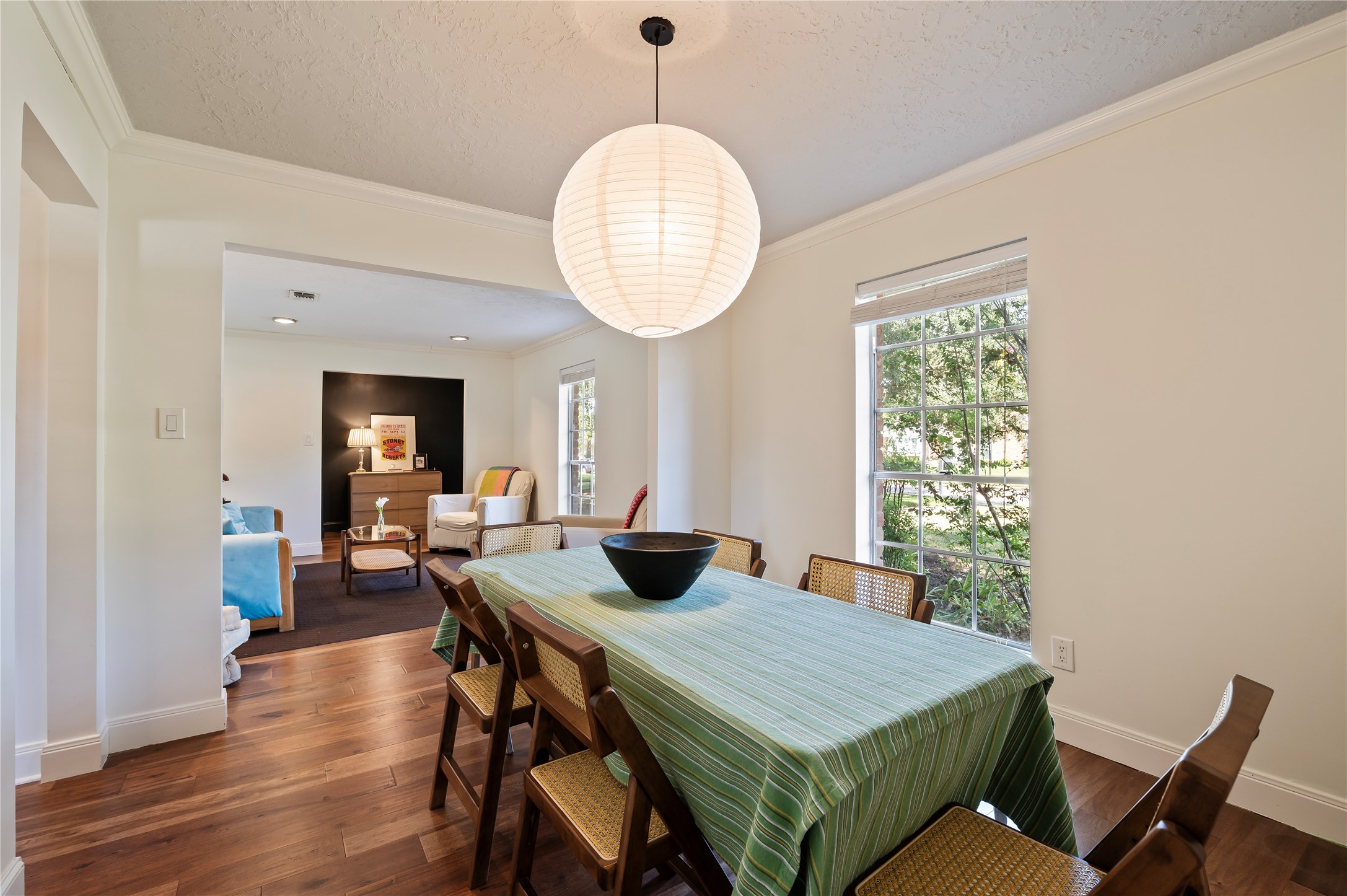 Spacious formal dining with wood like flooring, hanging light fixture and front yard views.