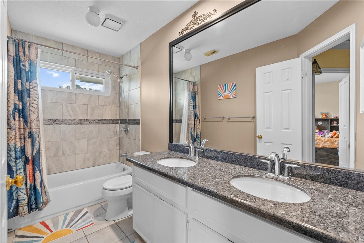 Dual sinks, granite counter-tops and framed mirror complete the secondary bathroom.
