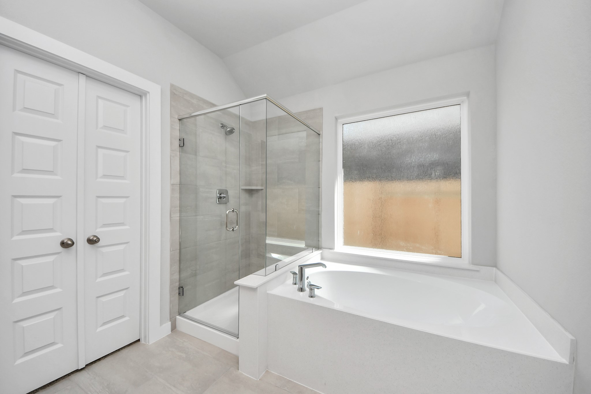 Indulge in a spa-like retreat within the confines of this primary bathroom. Delight in a spacious walk-in shower enveloped in stylish tile surround, unwind in a separate garden tub adorned with custom detailing. Sample photo of completed home with similar floor plan. Actual colors and selections may vary.