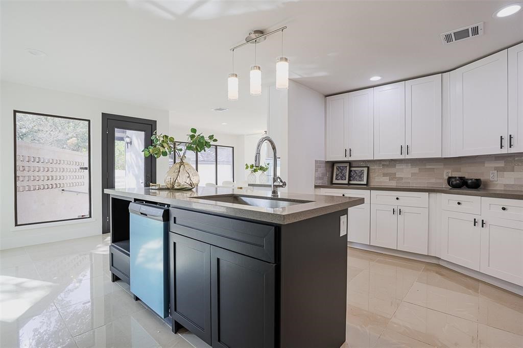 Striking black island with a sleek gray quartz countertop and integrated sink, creating a bold focal point in the kitchen. The combination of dark and light tones adds sophistication, complementing the overall design with both functionality and style.