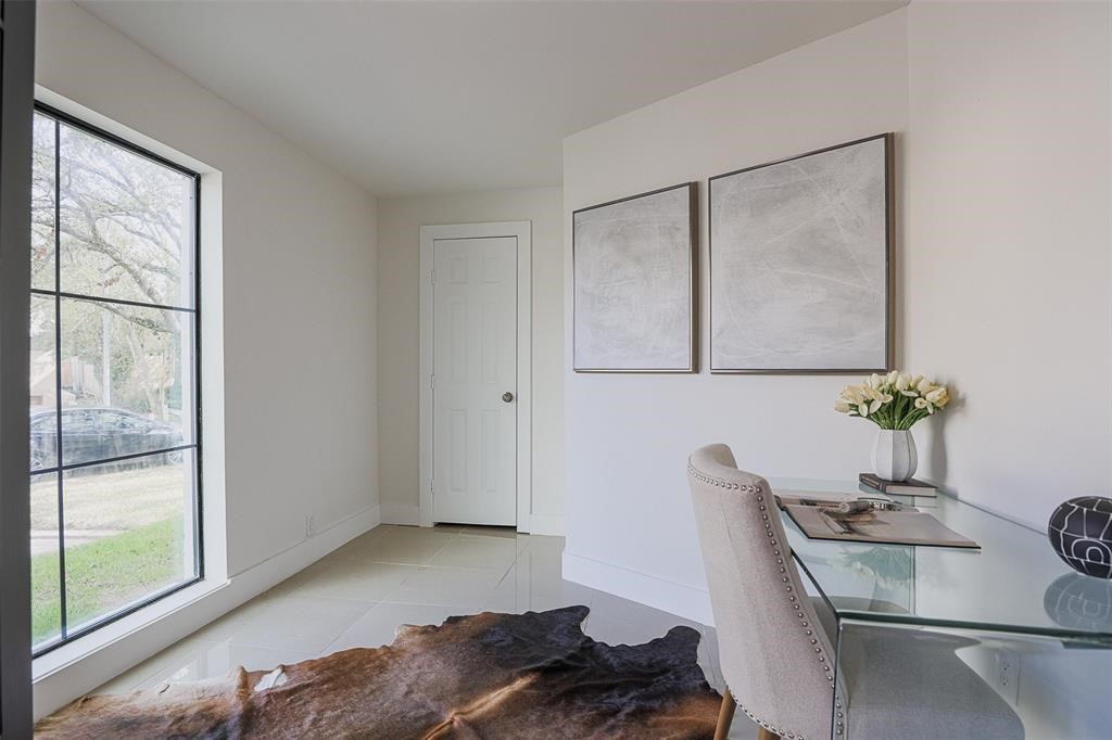 Private home office with large windows offering serene views of the meticulously manicured front yard. This refined workspace combines comfort and sophistication, featuring abundant natural light for a productive yet tranquil environment.