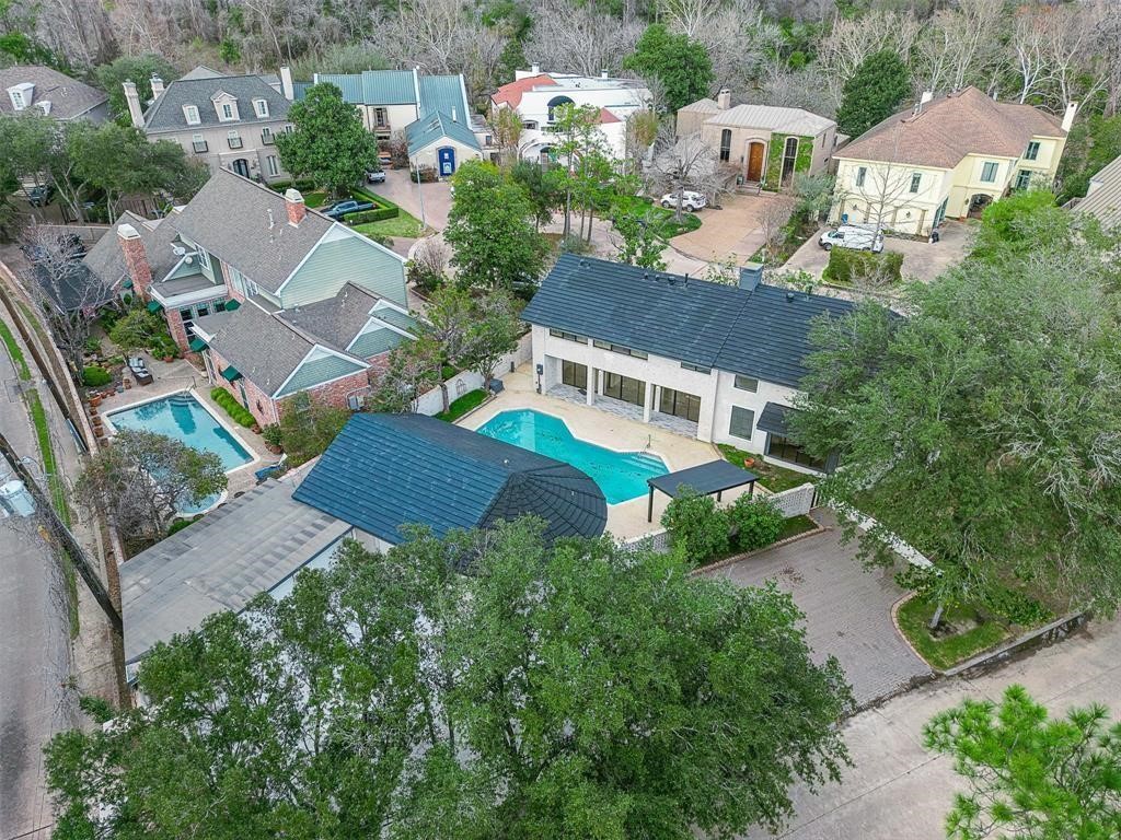 Aerial view of a spacious luxury property nestled in a quiet cul-de-sac, showcasing the elegant layout with the main house and guest house flanking a beautifully designed pool.