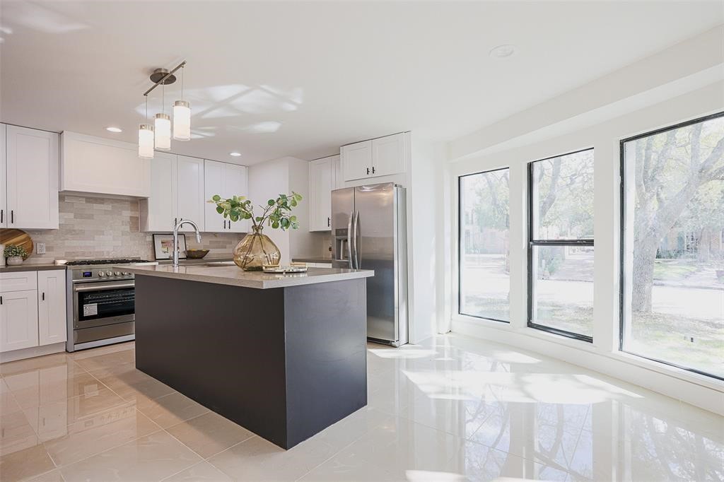 Sophisticated kitchen with expansive quartz countertops, abundant cabinetry, and large bay windows that frame a picturesque view of the front yard. The design seamlessly blends functionality and style, creating a bright and inviting space perfect for both cooking and casual dining.