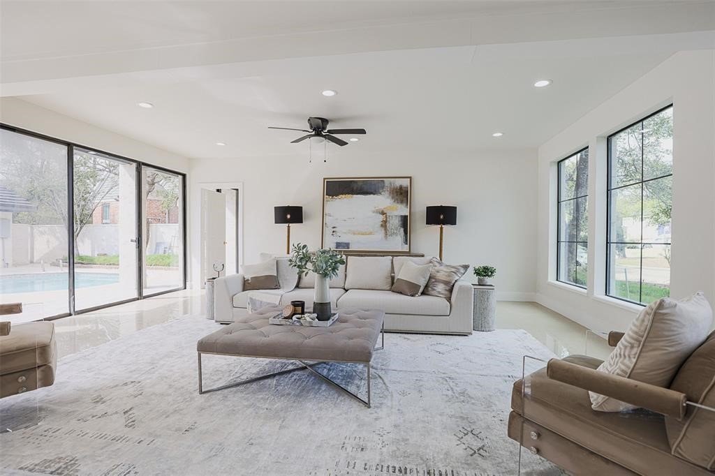 Bright and spacious living area featuring recessed lighting, elegant tile flooring, and expansive windows that flood the space with natural light. Enjoy seamless views of the pool to the left and the beautifully manicured front yard to the right, creating a perfect balance of indoor comfort and outdoor connection. Bright and spacious living area featuring recessed lighting, elegant tile flooring, and expansive windows that flood the space with natural light. Enjoy seamless views of the pool to the left and the beautifully manicured front yard to the right, creating a perfect balance of indoor comfort and outdoor connection.
