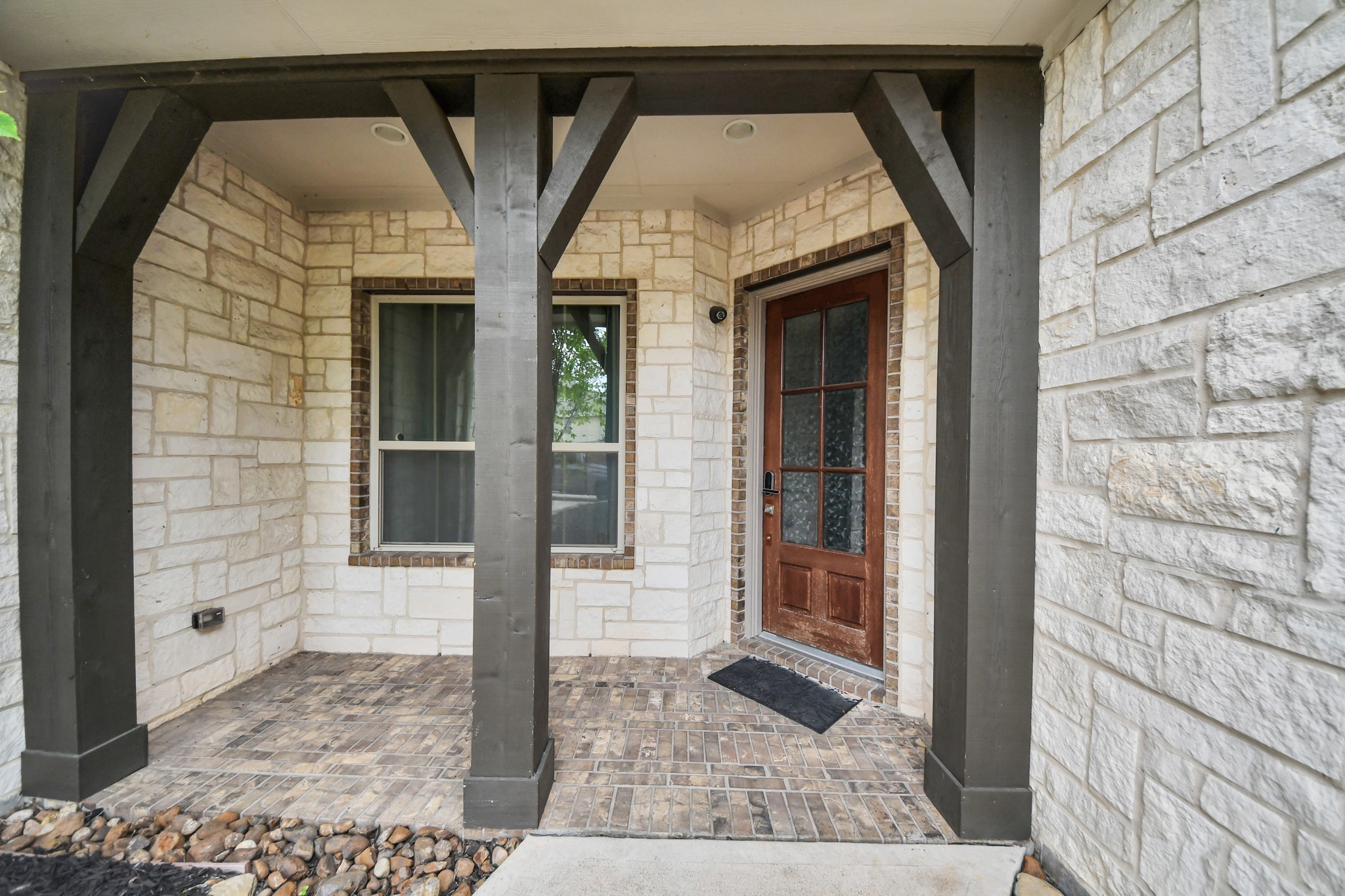Welcoming covered front porch featuring stone walls, brick flooring, and attractive architectural wood detailing. Welcoming covered front porch featuring stone walls, brick flooring, and attractive architectural wood detailing.