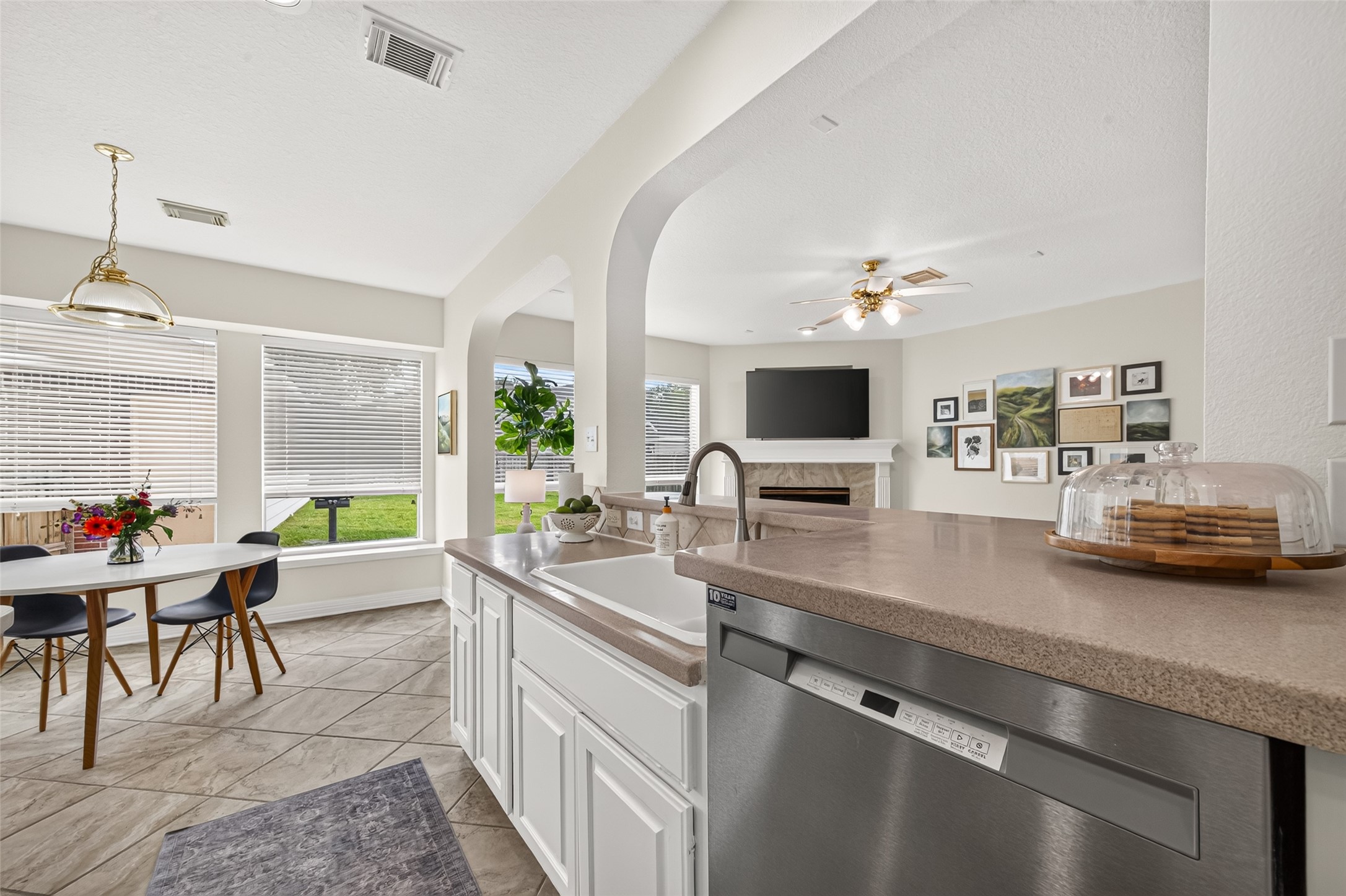 Bright and inviting open-concept space featuring a modern kitchen with a large island, adjoining a cozy living area with a fireplace, and a dining nook with abundant natural light.