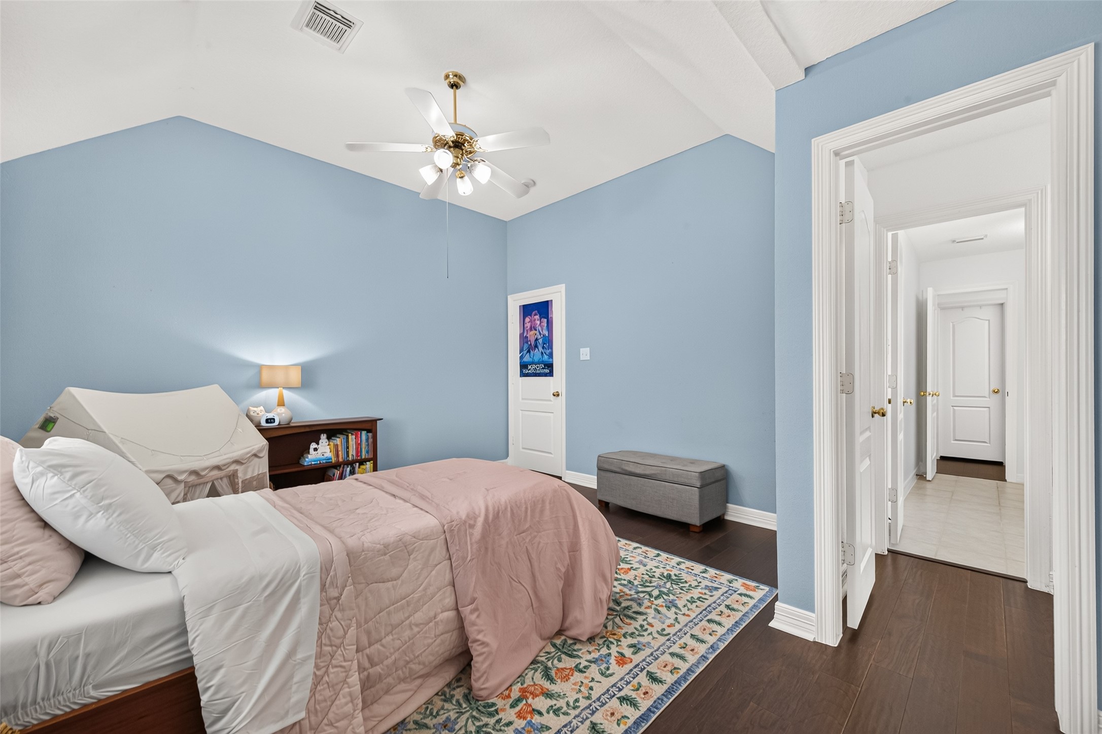 Second floor bedroom with vaulted ceiling, ceiling fan and abundant hardwood flooring.
