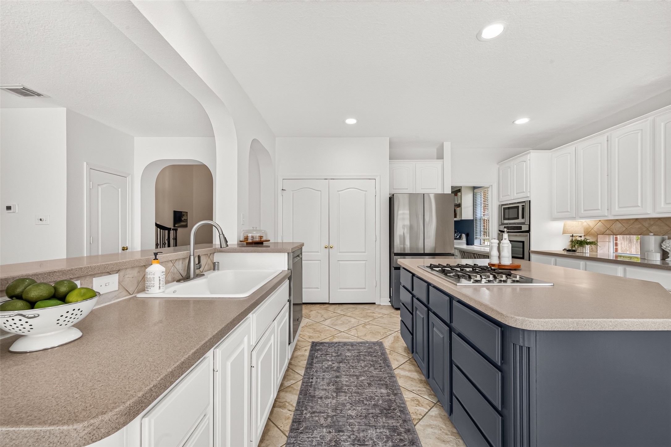 Spacious kitchen with modern stainless steel appliances, a large island with a gas cooktop, and elegant white cabinetry.