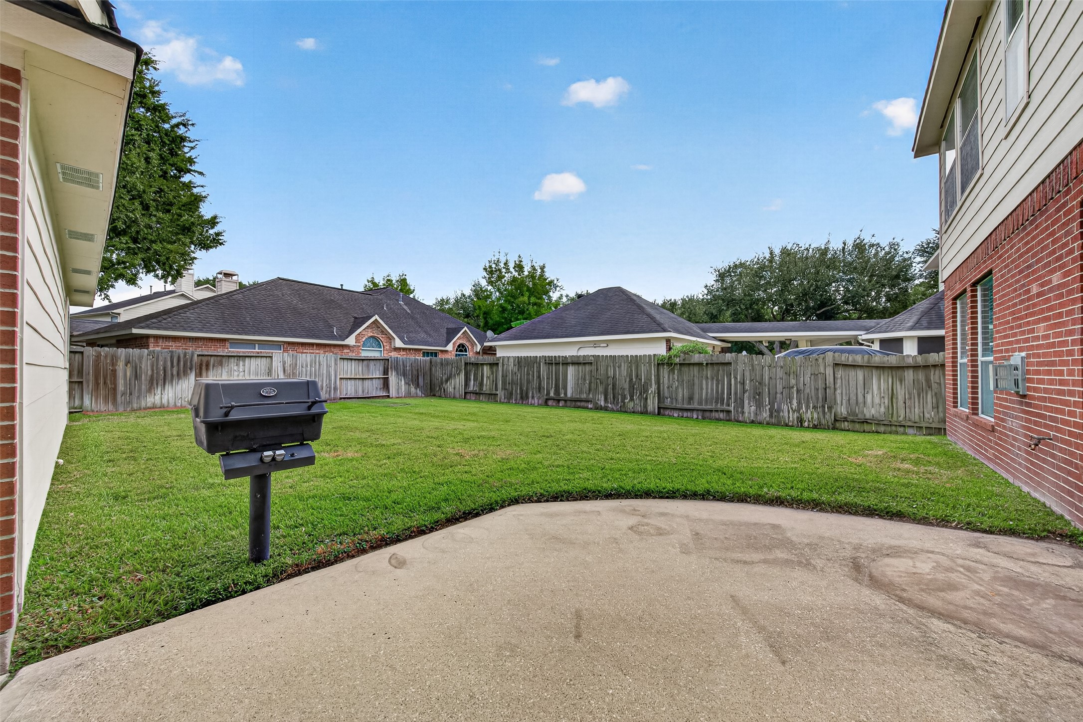 Spacious backyard with well maintained lawn, privacy fencing, and a built-in grill.