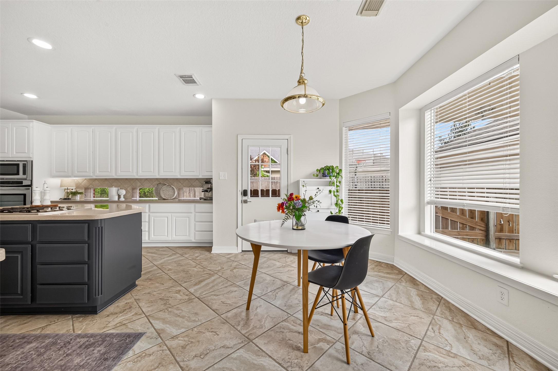 kitchen featuring abundant cabinetry, a central island with stainless steel appliances, and a cozy breakfast nook with bay windows.