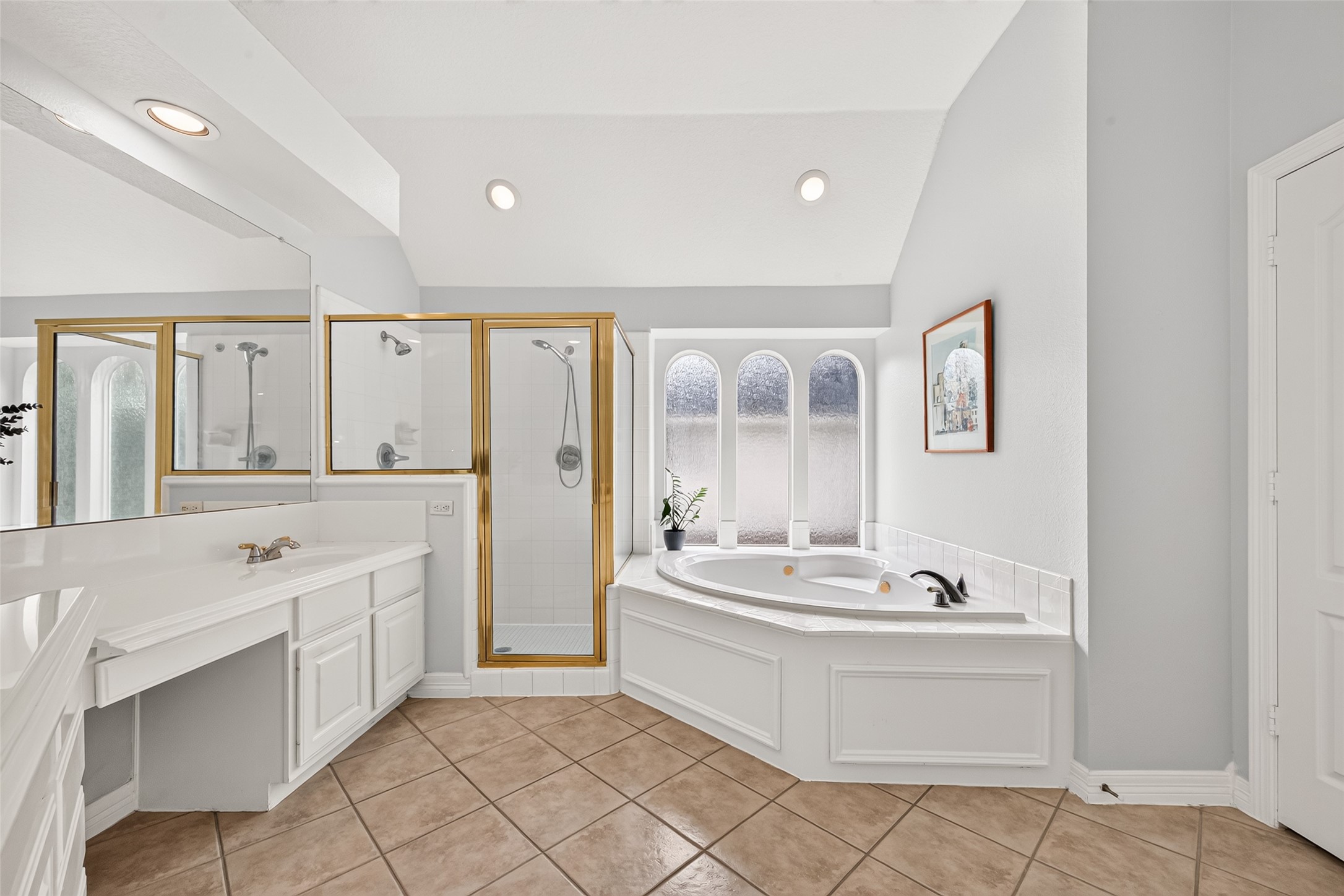 Primary bathroom featuring a spa like corner bathtub with a view, a separate glass enclosed shower and tile flooring.