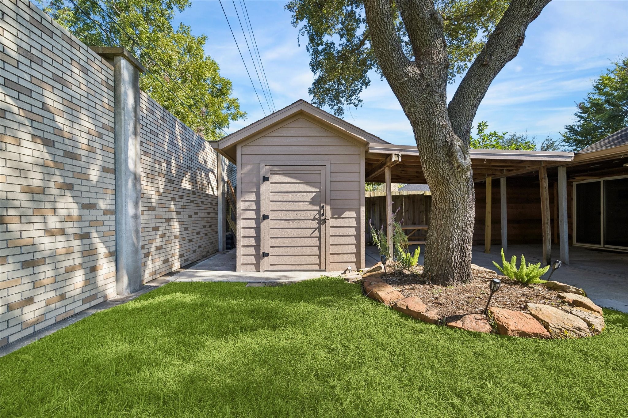 Enjoy the added convenience of a backyard climate-controlled storage shed, mature shade tree, and covered patio in this private outdoor setting.