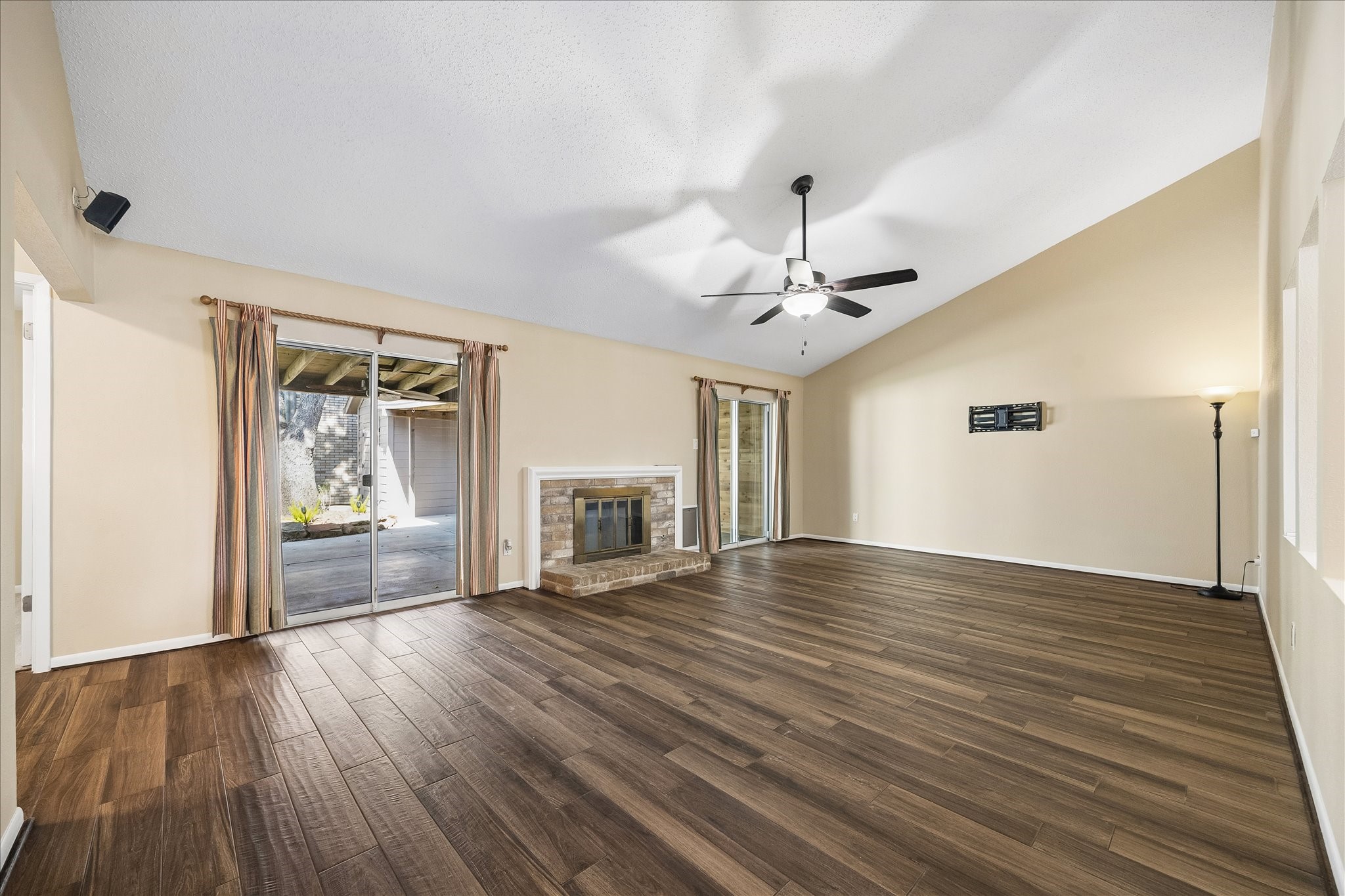 Imagine unwinding in this spacious living room that has been pre-wired with surround sound and is complete with a cozy fireplace, ceiling fan, and views of the backyard.