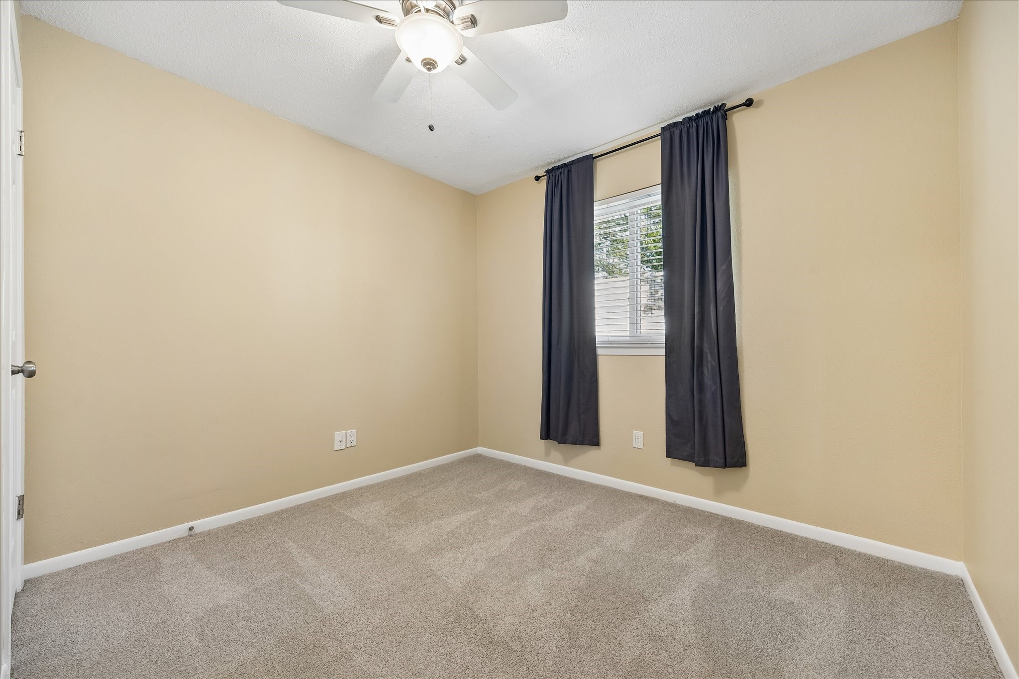 Create your own cozy retreat in this comfortable bedroom featuring soft carpeting, neutral colors, and a ceiling fan.