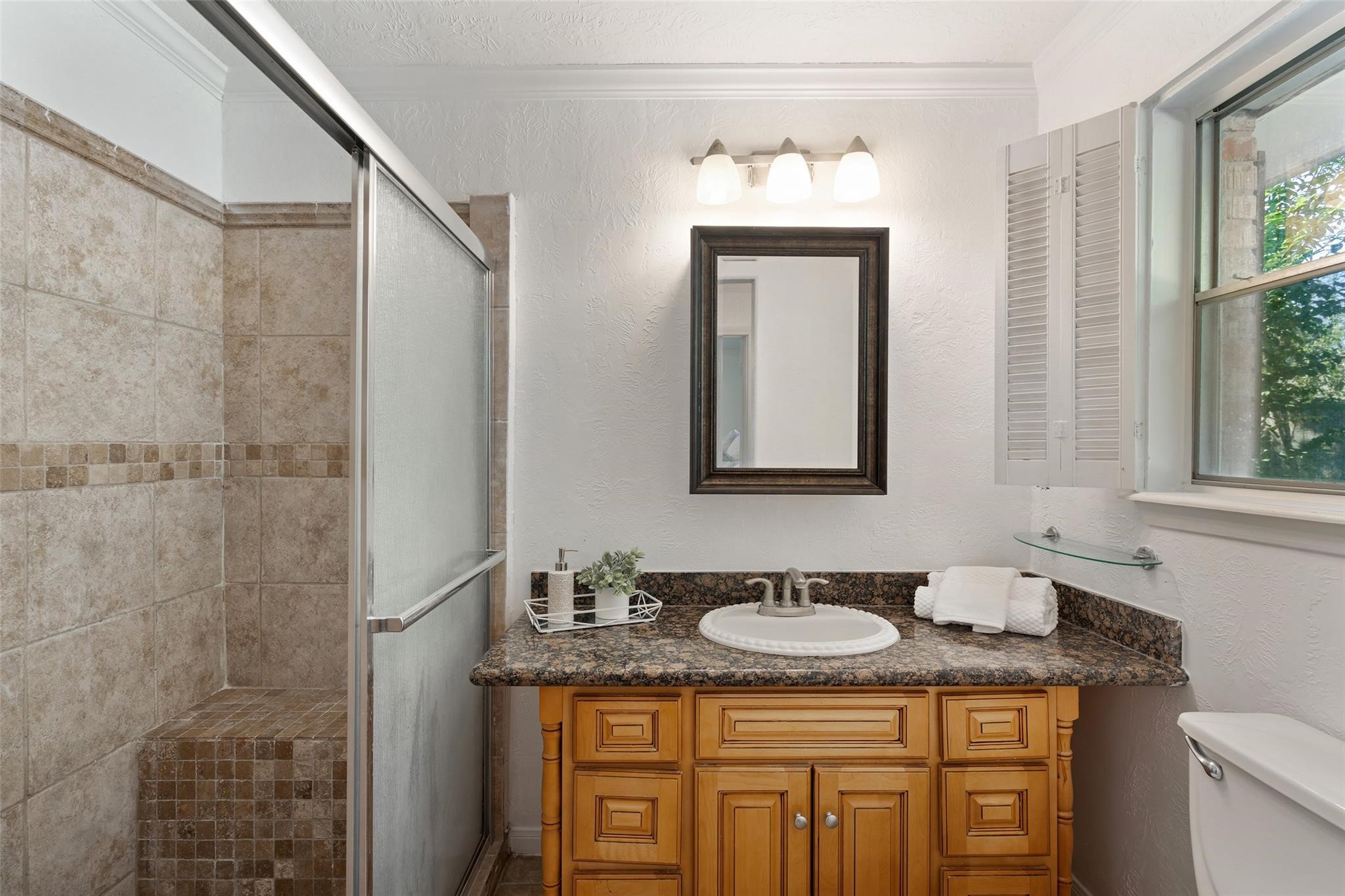 Beautiful tile design in the shower and large granite counter are wonderful features of the primary bathroom.*Home was previously furnished. There is currently no furniture in the home.