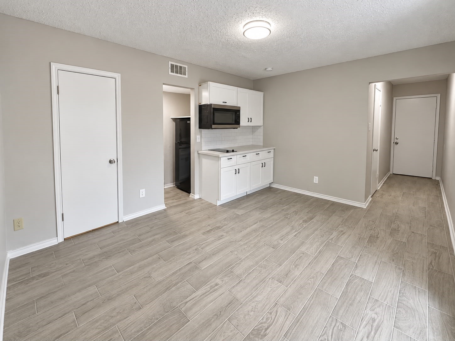 Open studio layout with kitchenette and entry hallway.