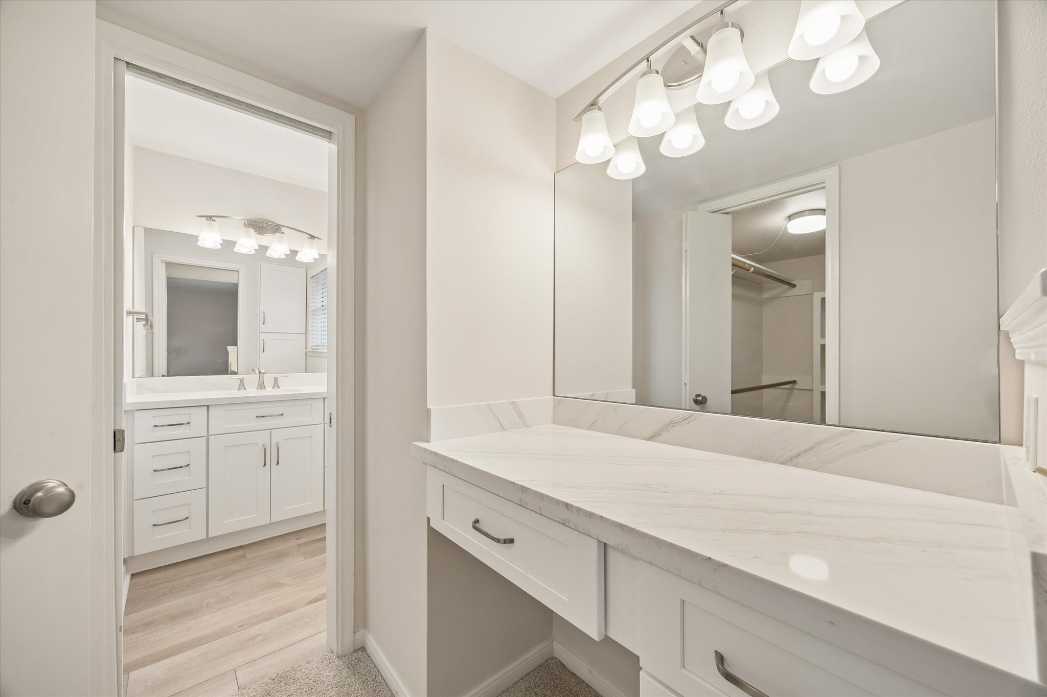 THE PRIMARY BATH INCLUDES A DEDICATED VANITY AREA WITH STONE COUNTERTOPS, AMPLE STORAGE, AND A LARGE WALL MIRROR.
