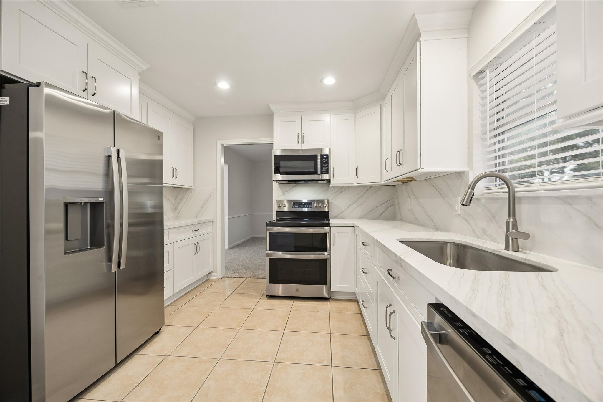 THE BRIGHT KITCHEN IS FINISHED WITH WHITE SHAKER-STYLE CABINETRY, STONE COUNTERTOPS, A FULL-HEIGHT BACKSPLASH, STAINLESS STEEL APPLIANCES, AND AMPLE STORAGE. THE BRIGHT KITCHEN IS FINISHED WITH WHITE SHAKER-STYLE CABINETRY, STONE COUNTERTOPS, A FULL-HEIGHT BACKSPLASH, STAINLESS STEEL APPLIANCES, AND AMPLE STORAGE.