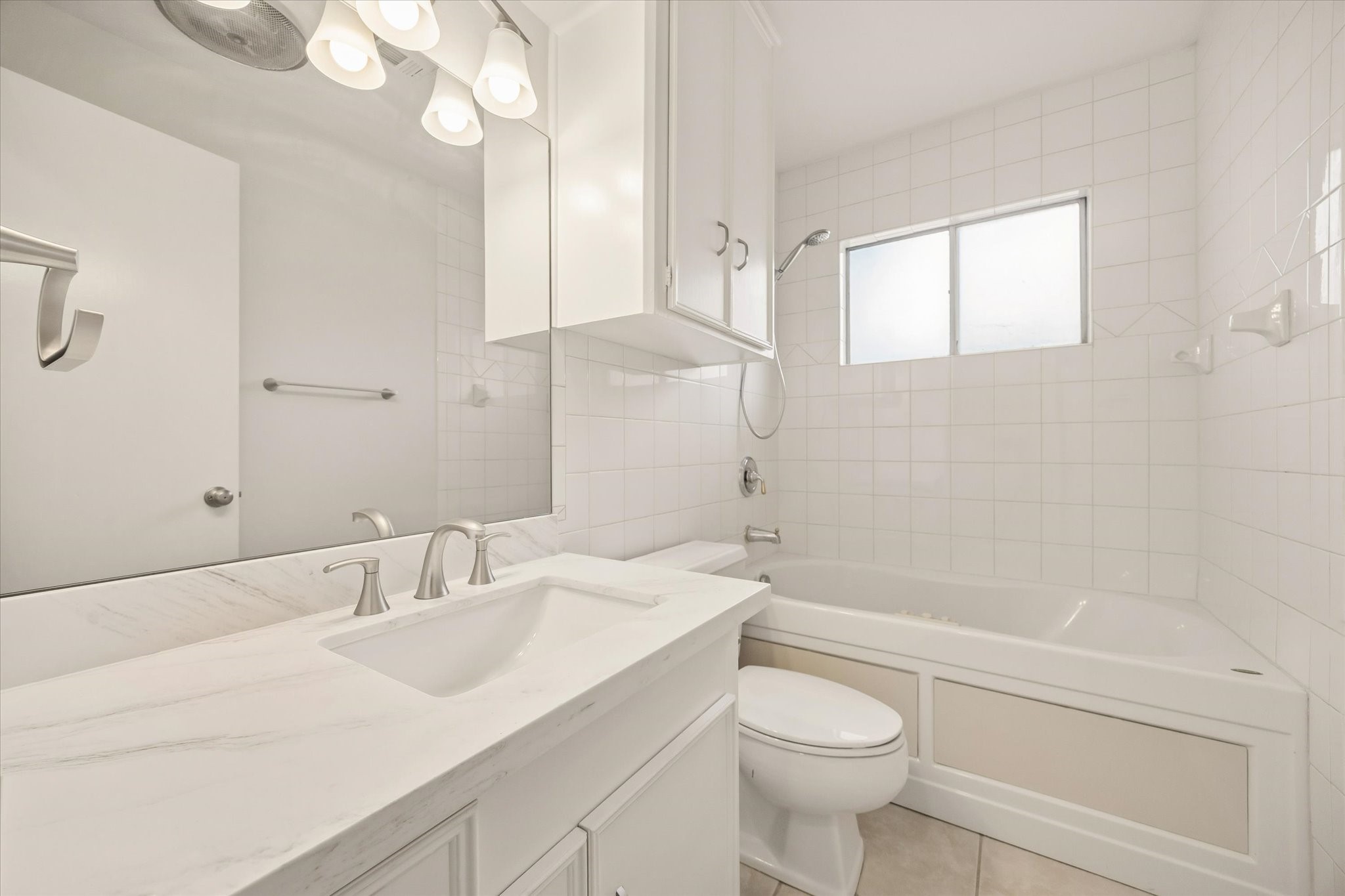 THE FULL BATH FEATURES A STONE-TOPPED VANITY, UNDERMOUNT SINK, AMPLE STORAGE, AND A TUB-SHOWER COMBINATION WITH TILE SURROUND.