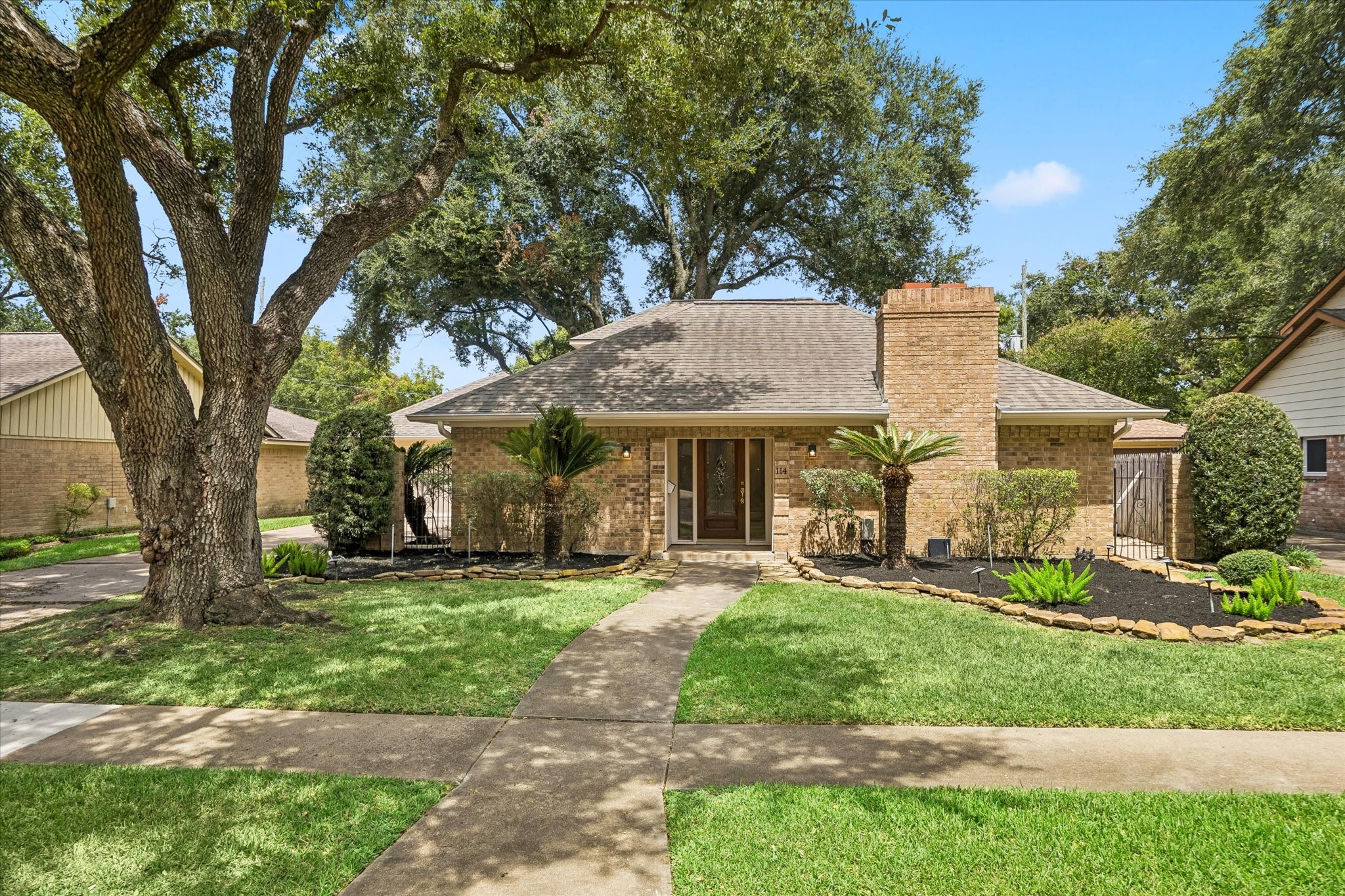THE INVITING FRONT EXTERIOR SHOWCASES TIMELESS BRICK, A PROMINENT CHIMNEY, AND A WALKWAY FRAMED BY MATURE LANDSCAPING. THE INVITING FRONT EXTERIOR SHOWCASES TIMELESS BRICK, A PROMINENT CHIMNEY, AND A WALKWAY FRAMED BY MATURE LANDSCAPING.