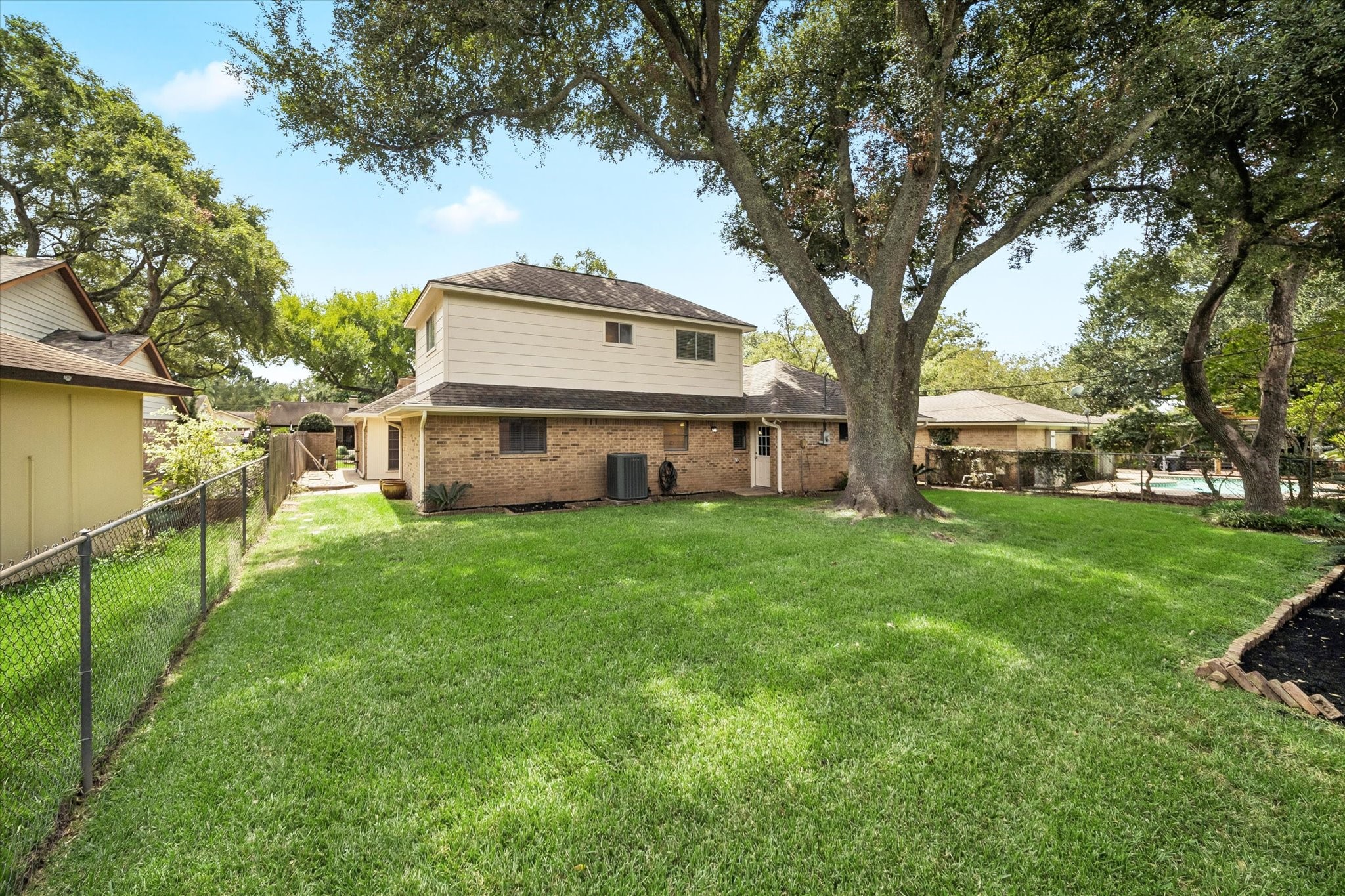 THE SPACIOUS BACKYARD OFFERS A LARGE LAWN, MATURE SHADE TREES, AND PLENTY OF ROOM FOR OUTDOOR LIVING OR PLAY.