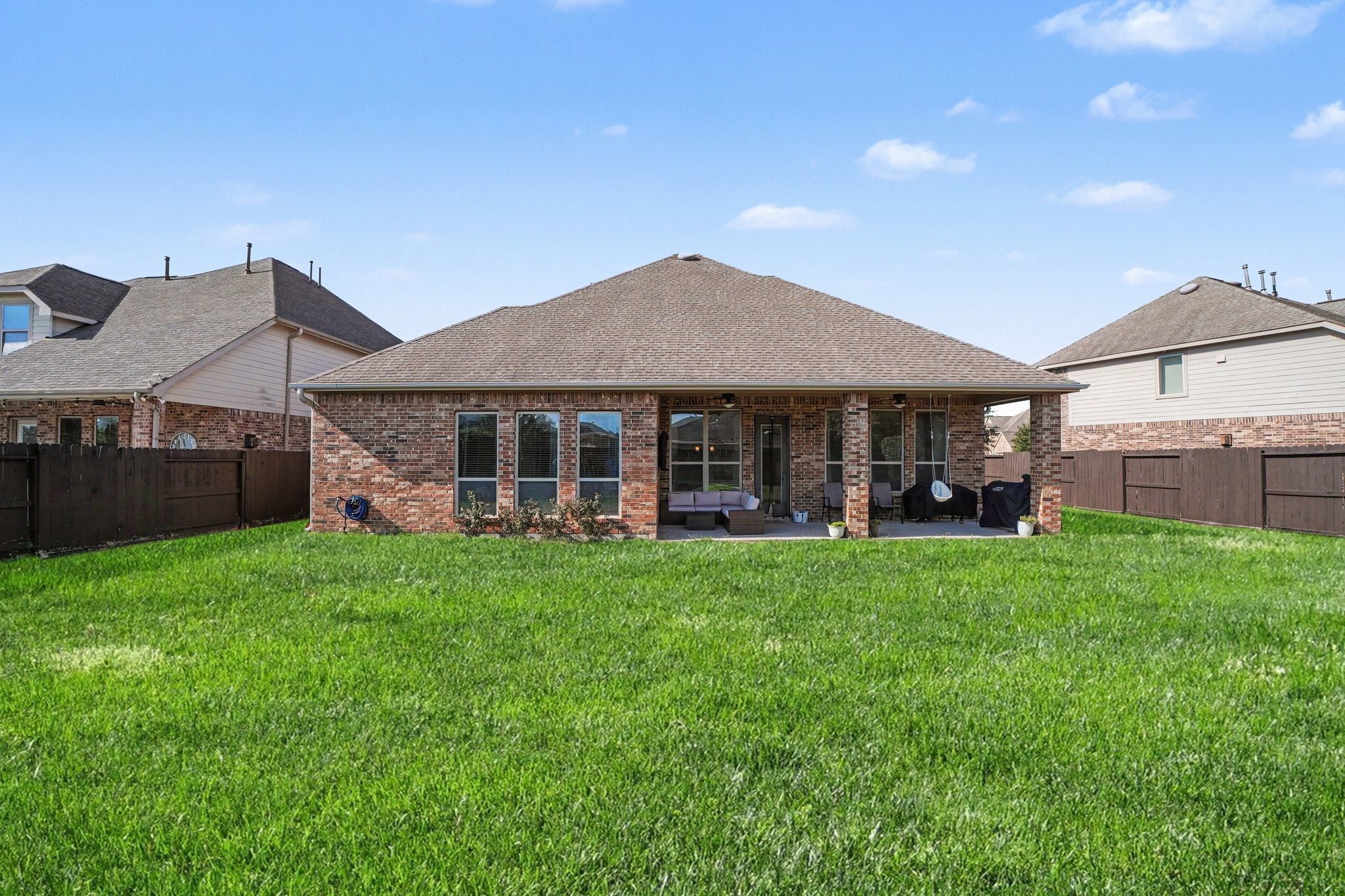 Step out into a vast outdoor haven featuring an expansive, fully fenced backyard with endless possibilities for relaxation, play, and outdoor entertaining. The rear exterior showcases timeless, classic brick masonry and a large covered patio supported by handsome brick columns.
