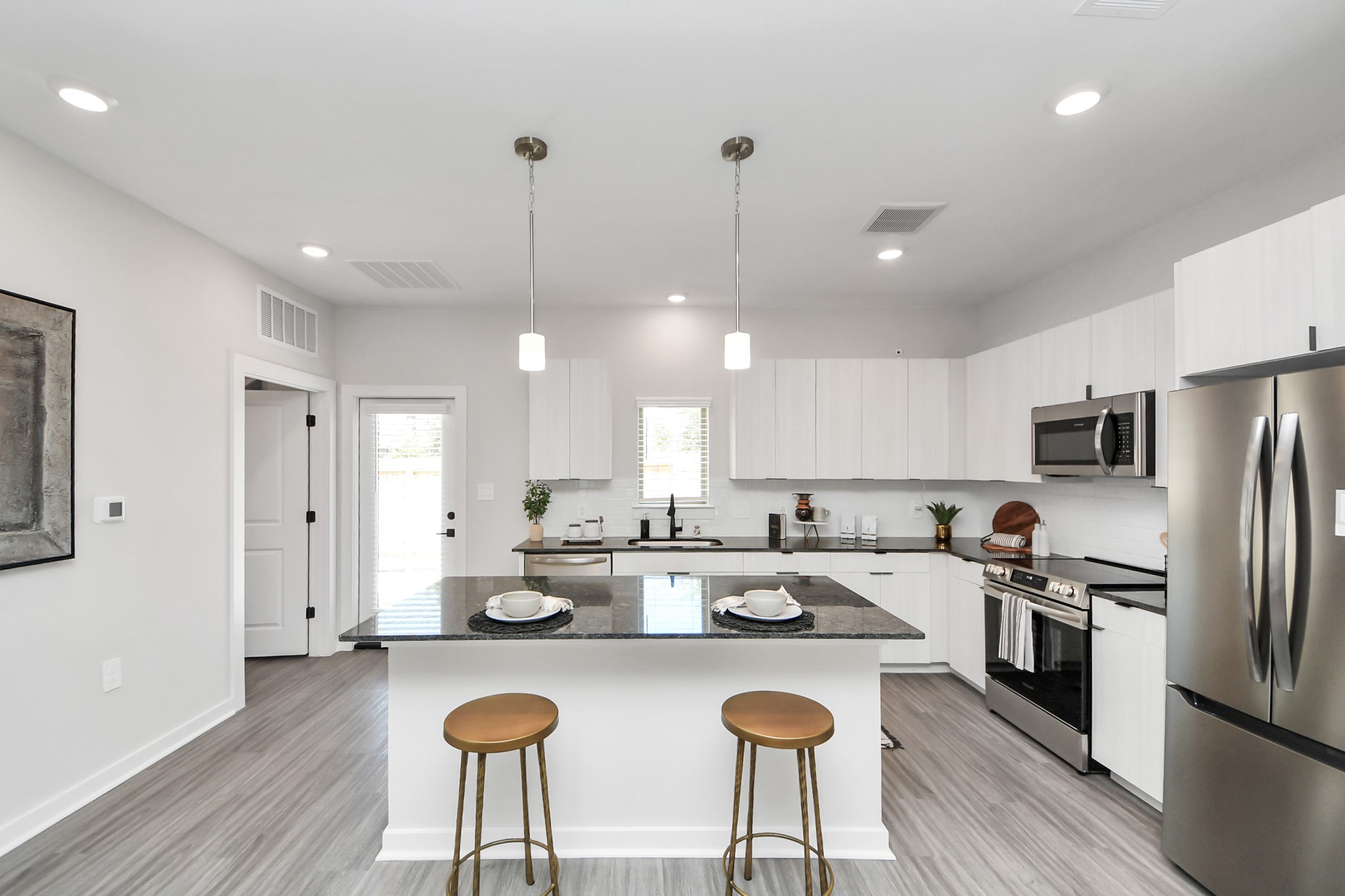 Boasting luxury finishes-stylish Island kitchen,granite counters,subway tile backsplash,ample custom cabinet space,stainless appliances,refrigerator,full size washer&dryer included,wood-like flooring throughout,open concept floor plan.