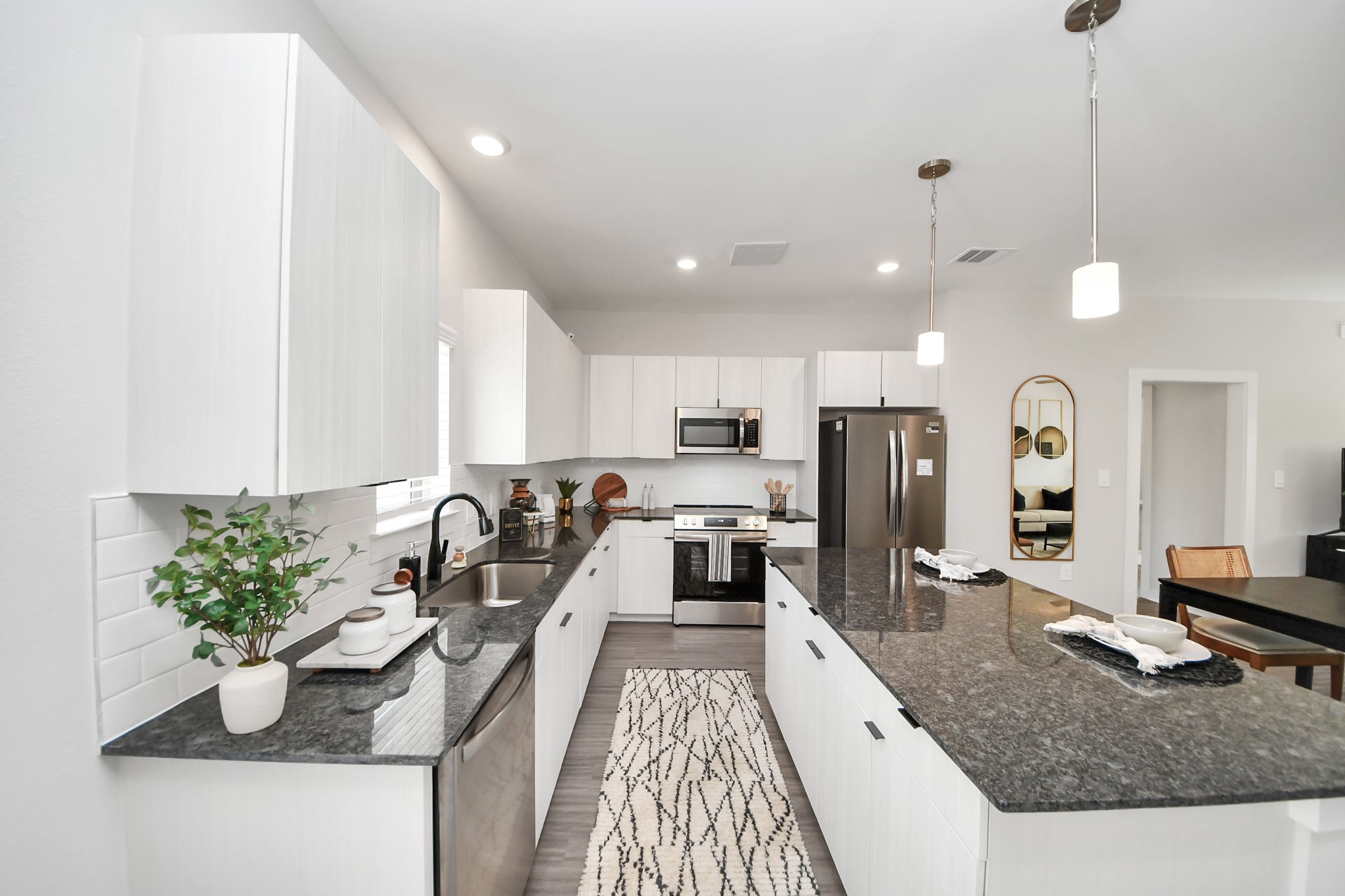 Boasting luxury finishes-stylish Island kitchen,granite counters,subway tile backsplash,ample custom cabinet space,stainless appliances,refrigerator,full size washer&dryer included,wood-like flooring throughout,open concept floor plan.